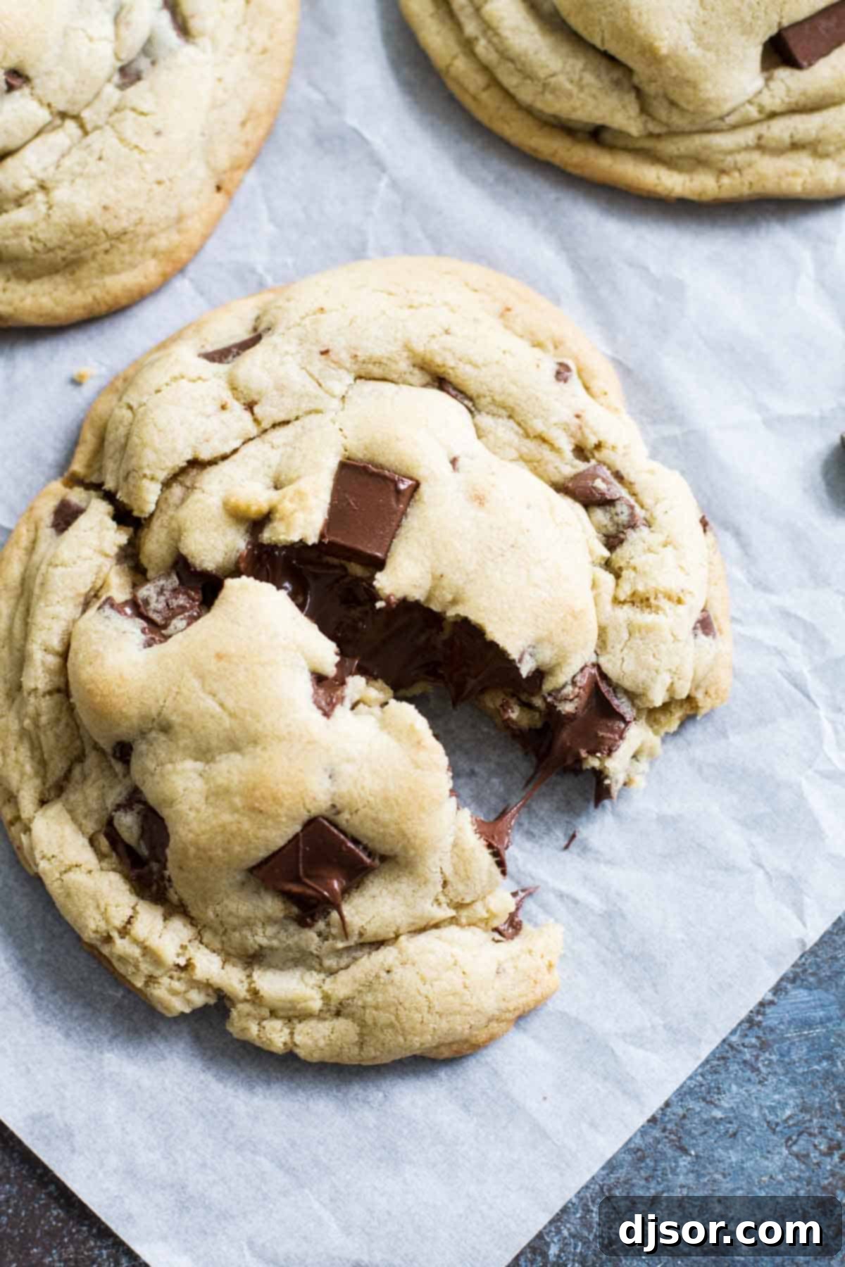 The Art of Perfect Giant Chocolate Chip Cookies Giant Chocolate Chip Cookies, with one broken in half to reveal the soft, chewy interior.