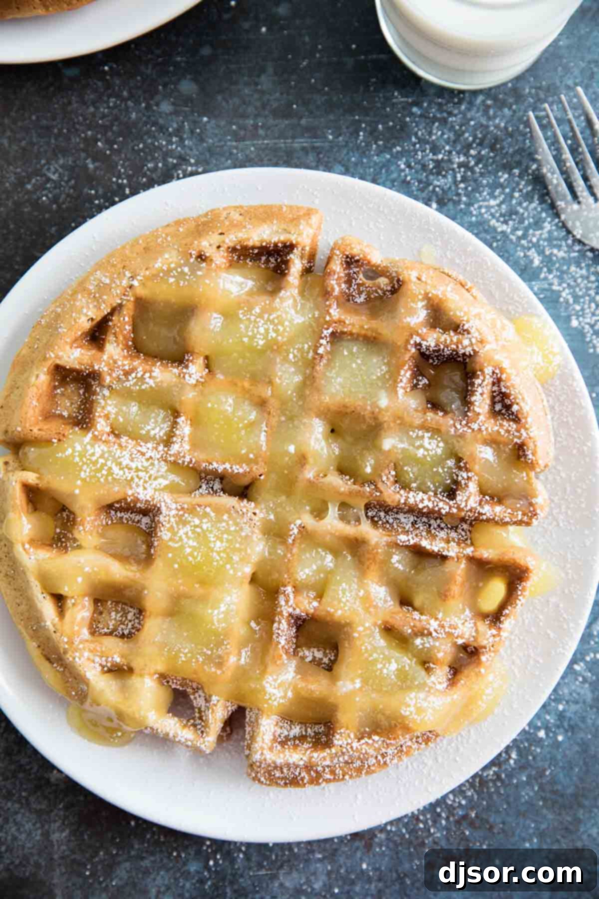 A single gingerbread waffle on a white plate, artfully topped with lemon sauce, ready to be enjoyed.