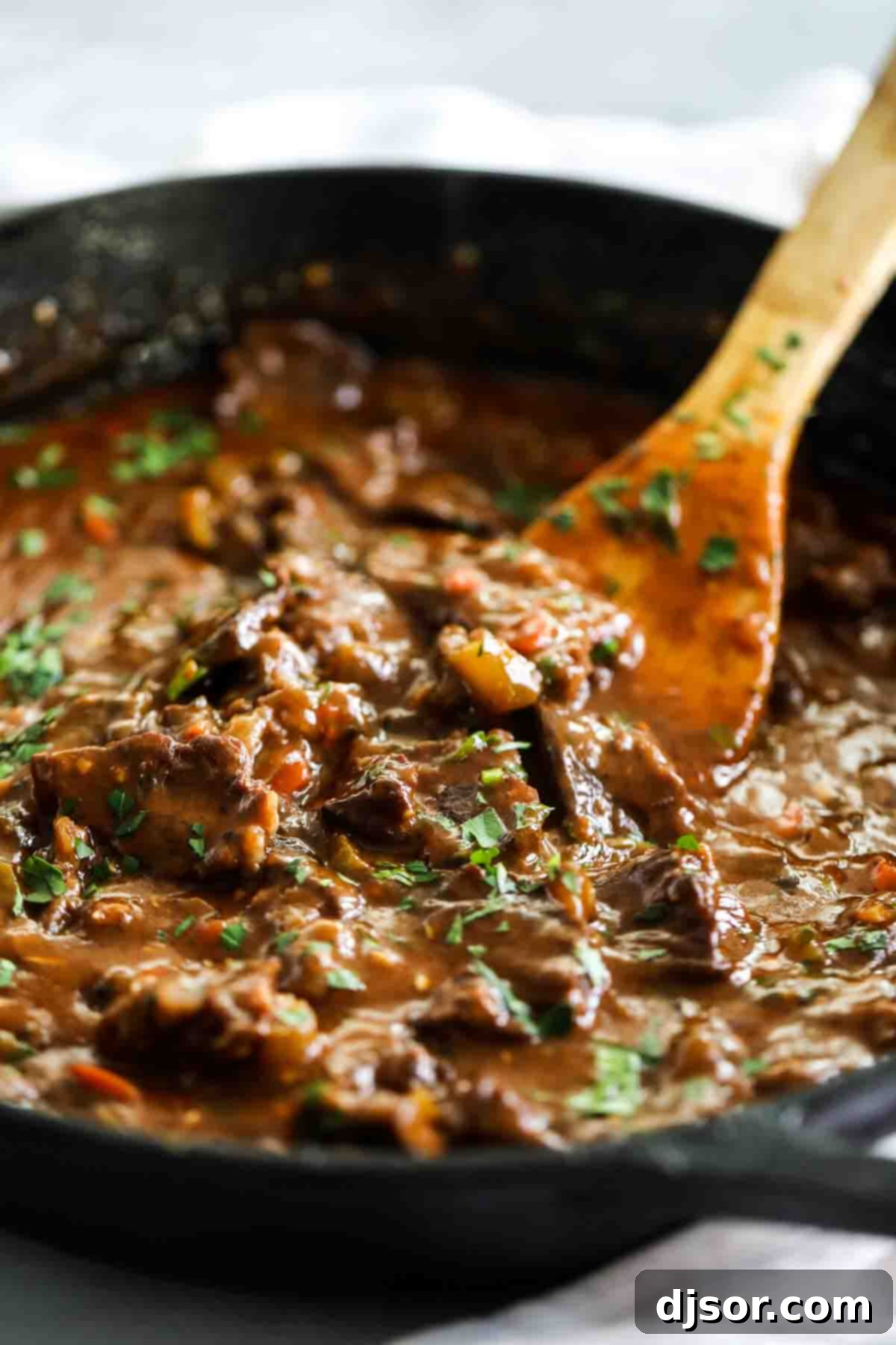 A classic comfort meal, this Beef Tips and Gravy cooks pieces of beef in a homemade gravy until it is super tender and flavorful. Serve over mashed potatoes, rice or noodles for the perfect Sunday supper that the whole family will go crazy over. beef tips and gravy in a skillet with a wooden spoon