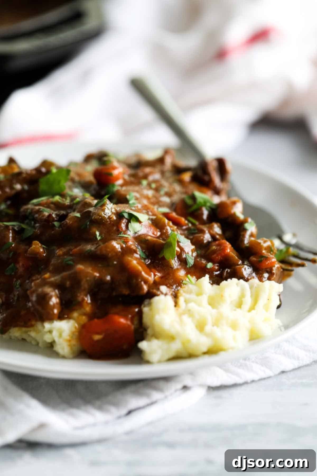 A classic comfort meal, this Beef Tips and Gravy cooks pieces of beef in a homemade gravy until it is super tender and flavorful. Serve over mashed potatoes, rice or noodles for the perfect Sunday supper that the whole family will go crazy over. beef tips and gravy over mashed potatoes on a plate