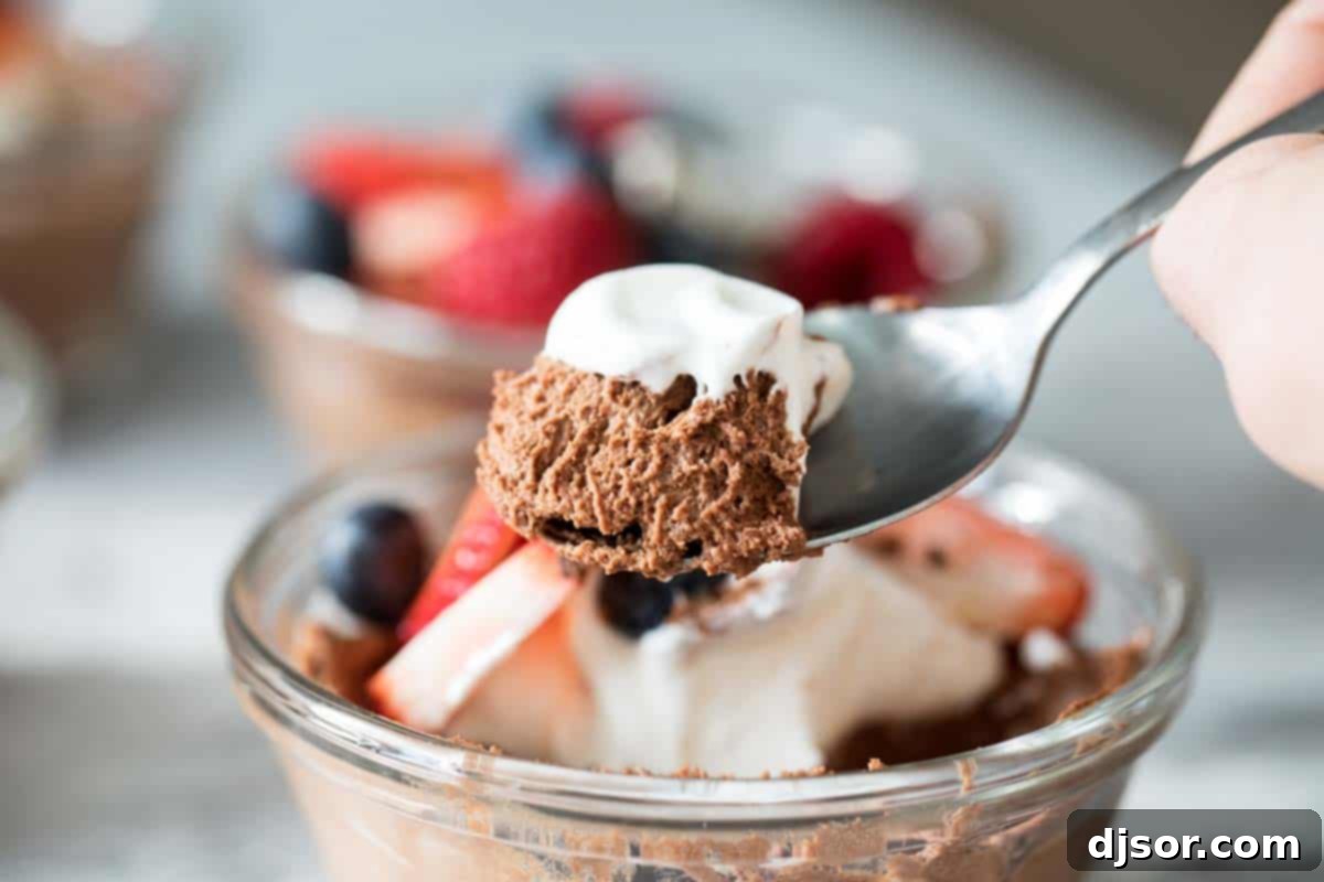 Extremely close-up shot revealing the airy, delicate, and porous texture of dark chocolate mousse in a clear glass bowl, showcasing its light and fluffy consistency.