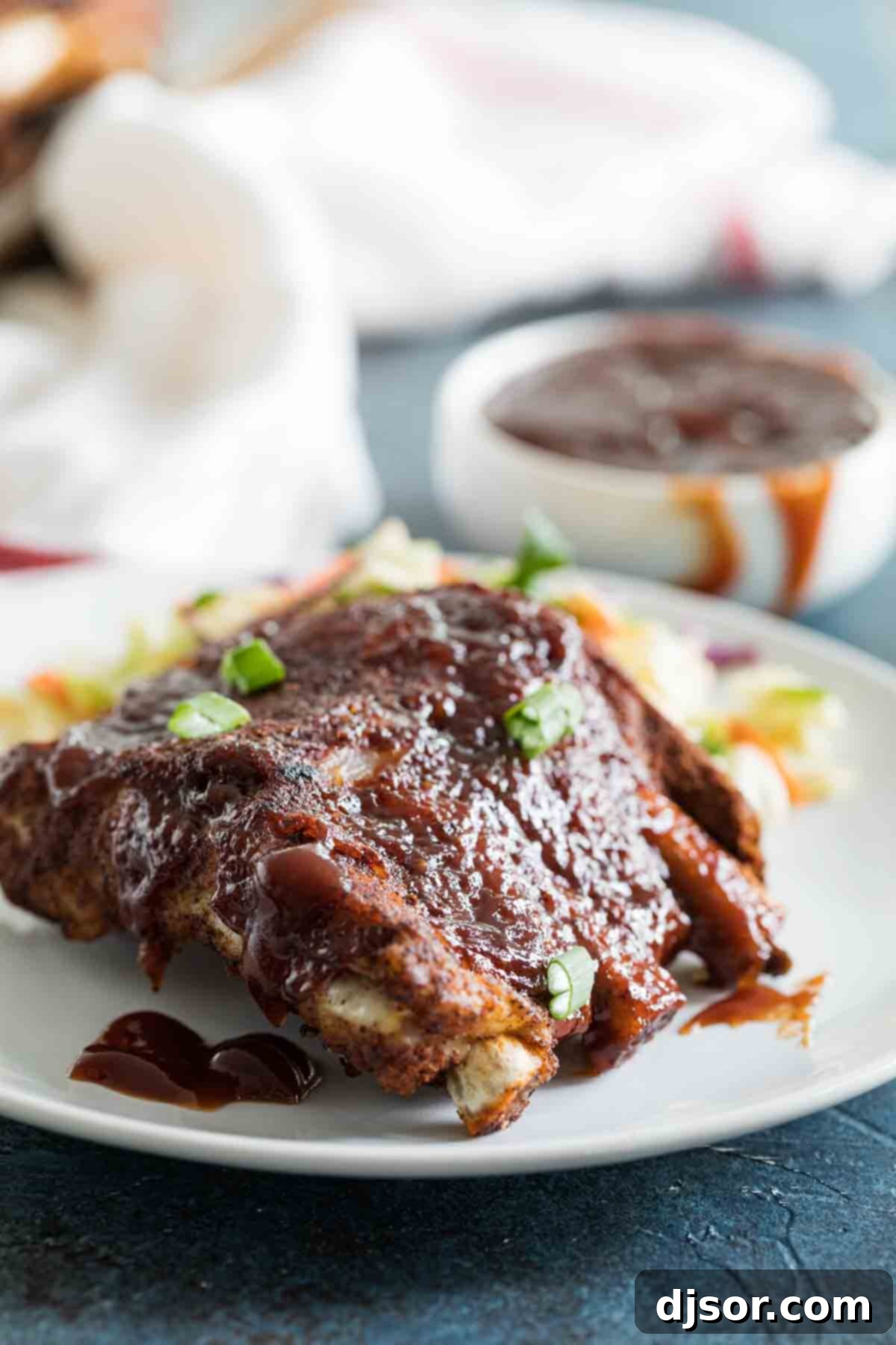 Plate of tender Instant Pot Ribs with rich barbecue sauce, garnished with fresh herbs.