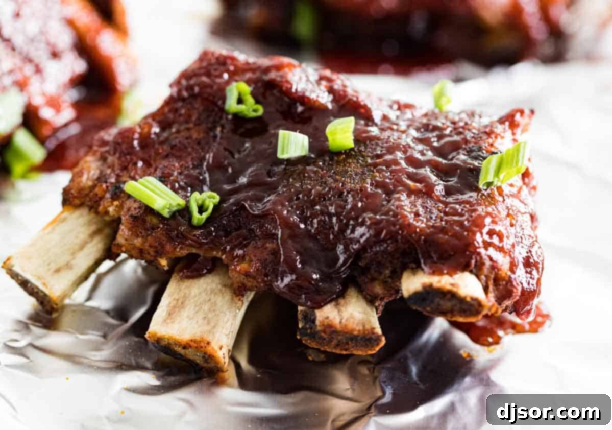Cooked Instant Pot Ribs, glazed with barbecue sauce and sprinkled with fresh green onions, on a serving plate.