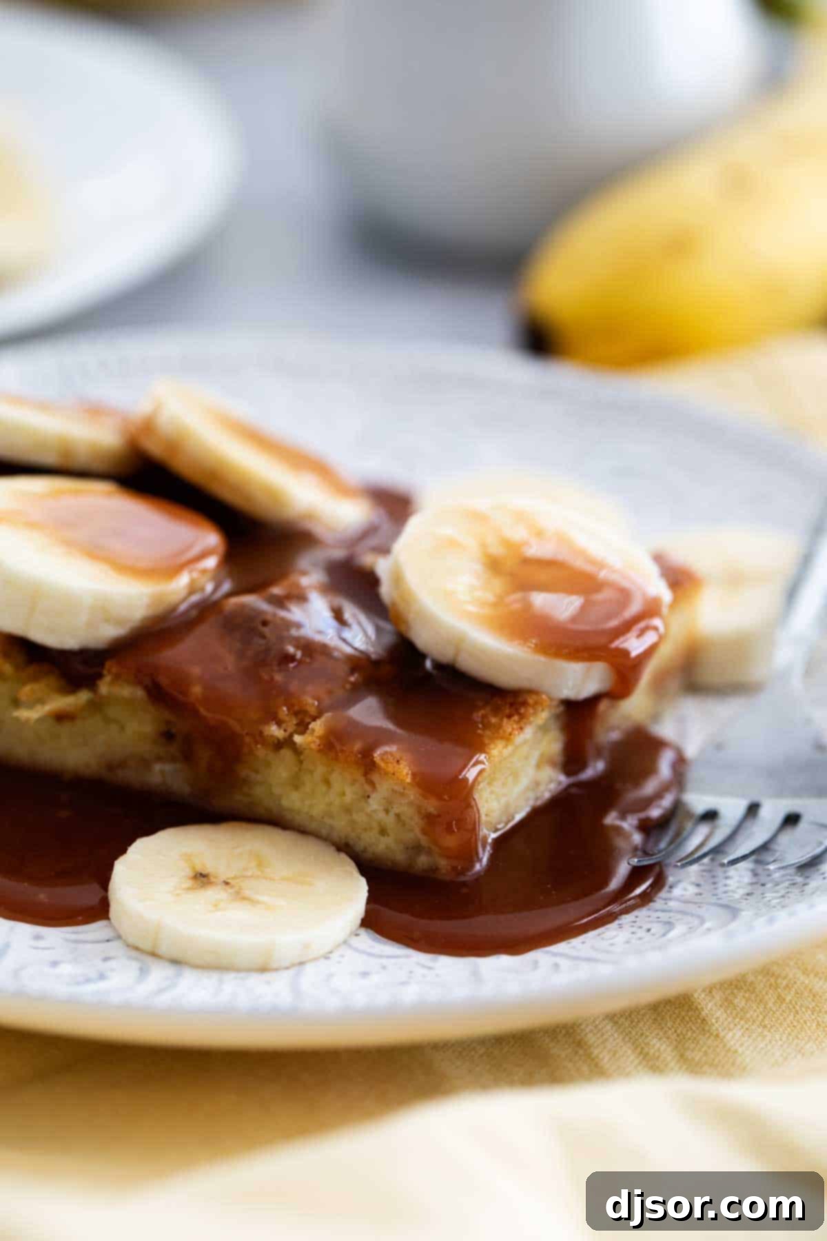 Disneyland Style Brioche French Toast Slice Slice of copycat Disneyland Brioche French Toast. A single, thick slice of golden-brown brioche French toast topped with a generous amount of salted caramel sauce and fresh banana slices.