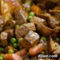 Chili beef and vegetables in a pot with a wooden spoon.