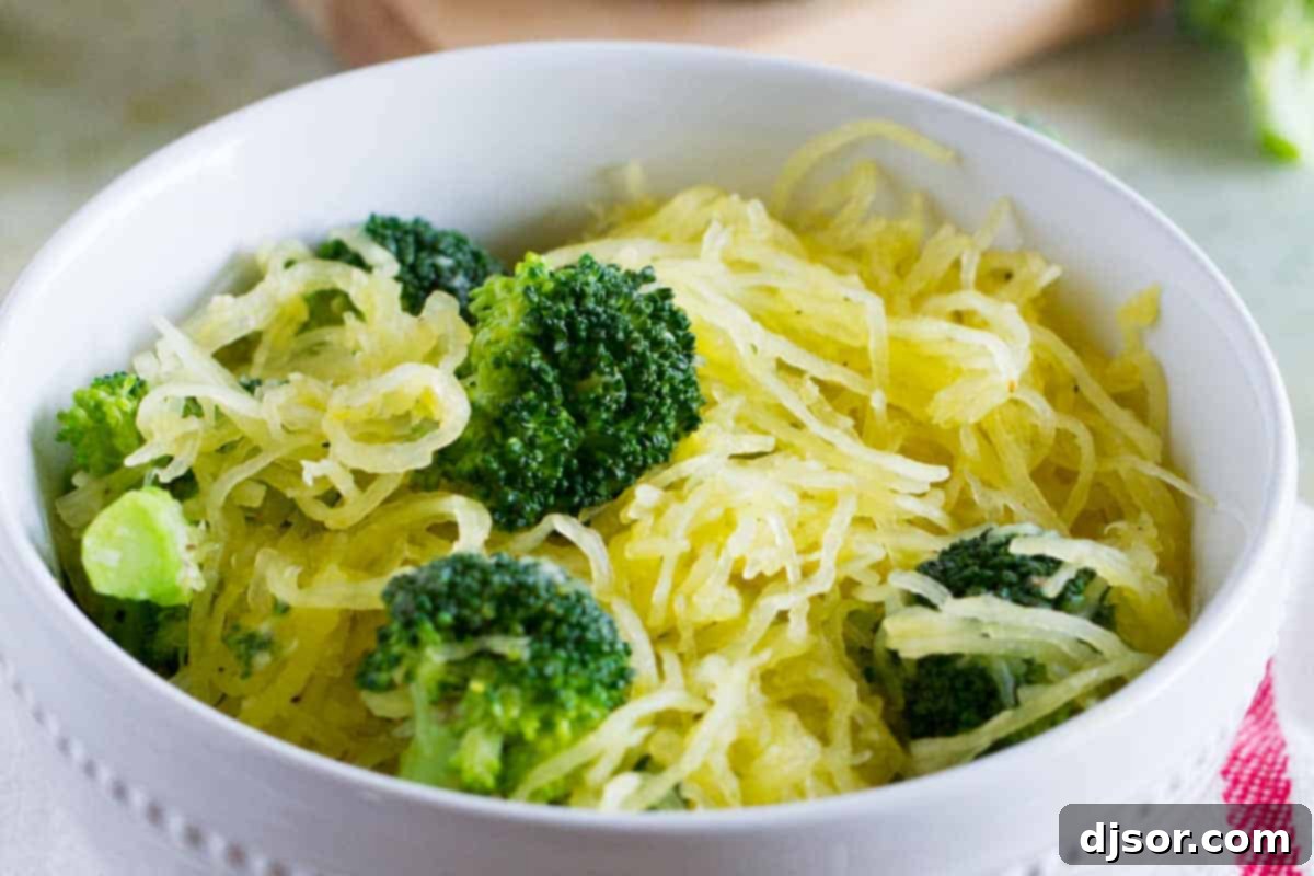 A close-up view of a steaming bowl of spaghetti squash and broccoli, garnished with fresh herbs.