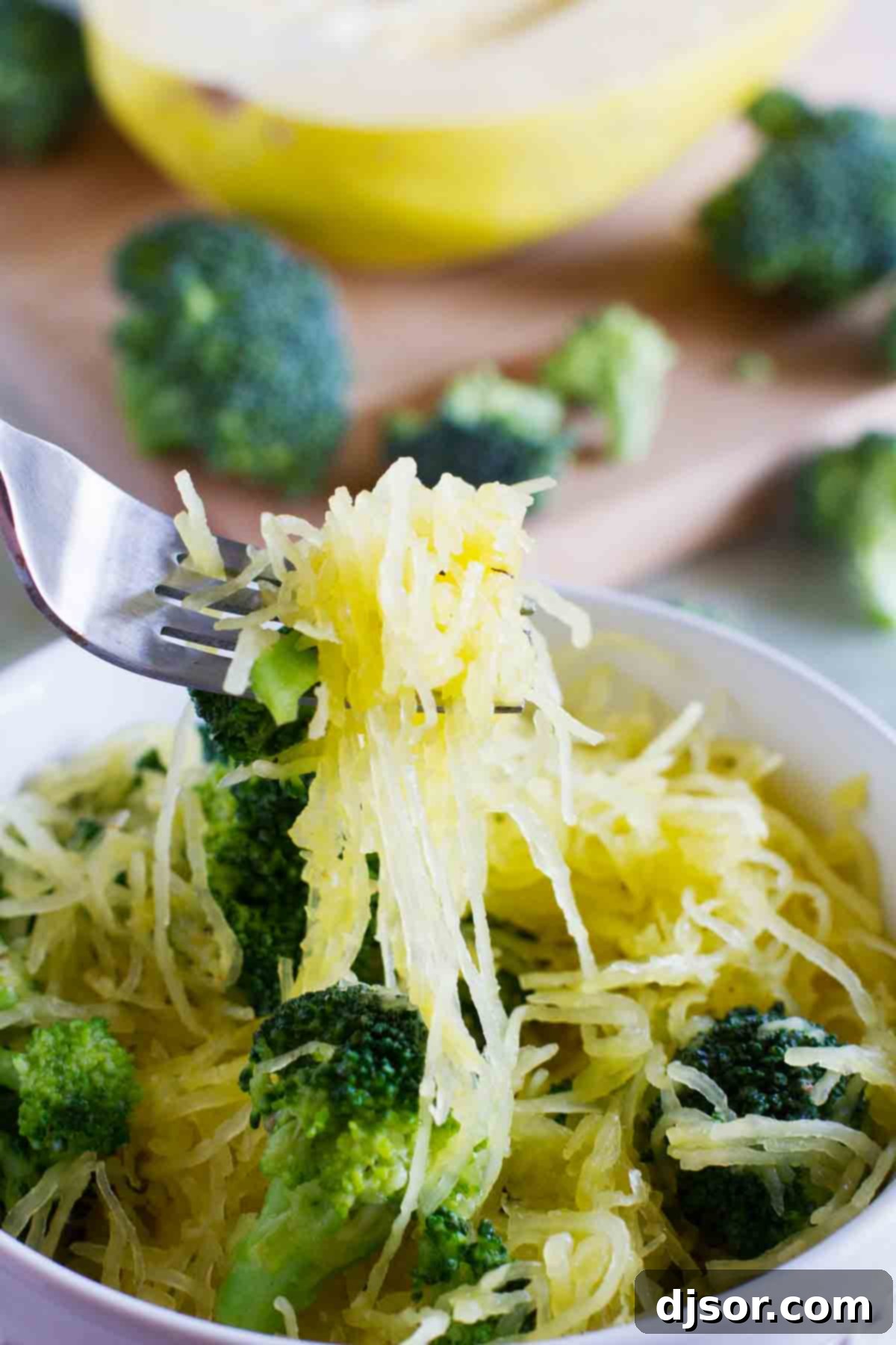 A fork lifts a generous portion of spaghetti squash and broccoli from a bowl, showcasing the healthy and vibrant meal.