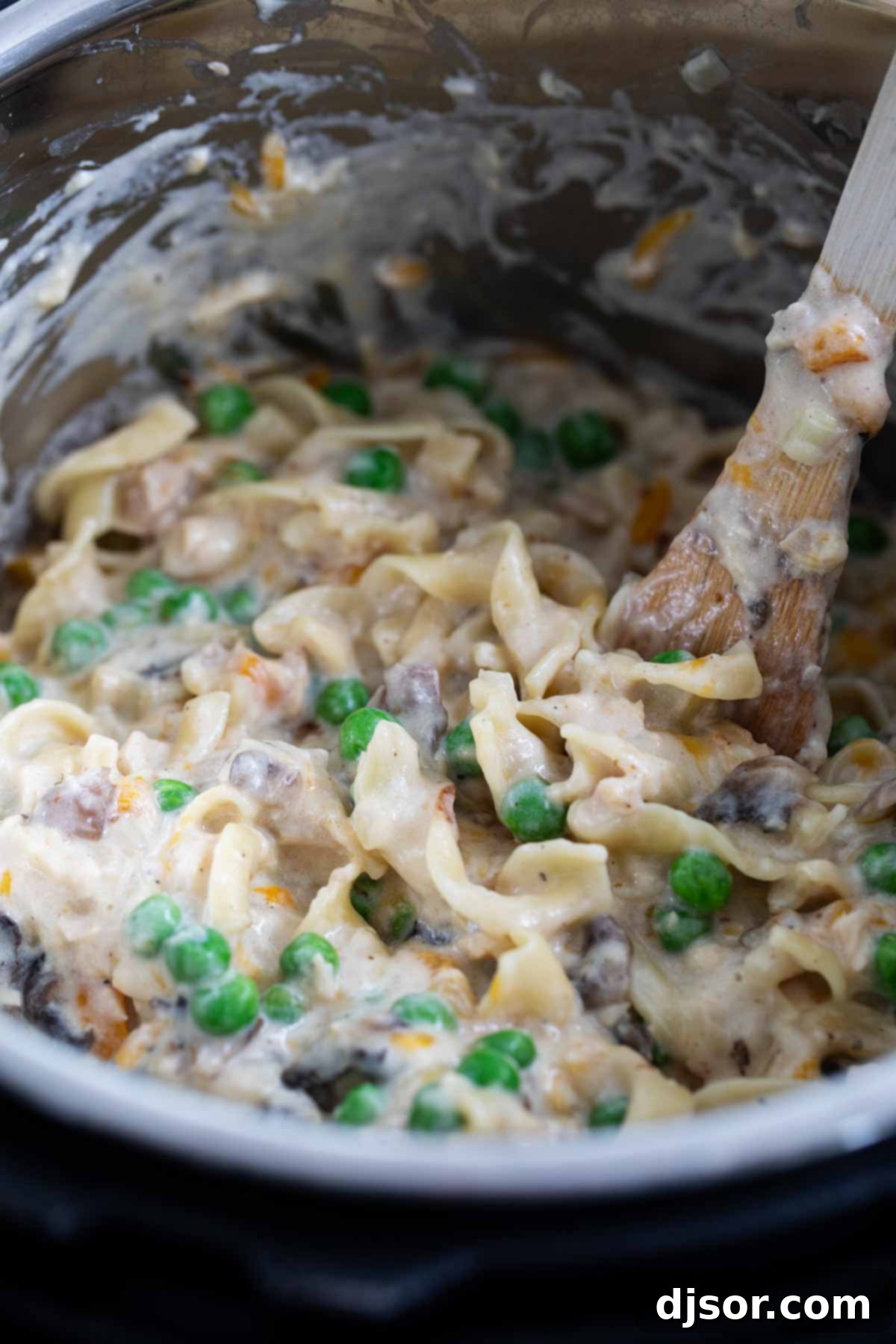 Creamy, cheesy and always comforting, this Instant Pot Tuna Noodle Casserole is so easy you’ll never bake it again. And bonus - this recipe is made from scratch! Preparing homemade Tuna Noodle Casserole in an Instant Pot, showing the ingredients being stirred.