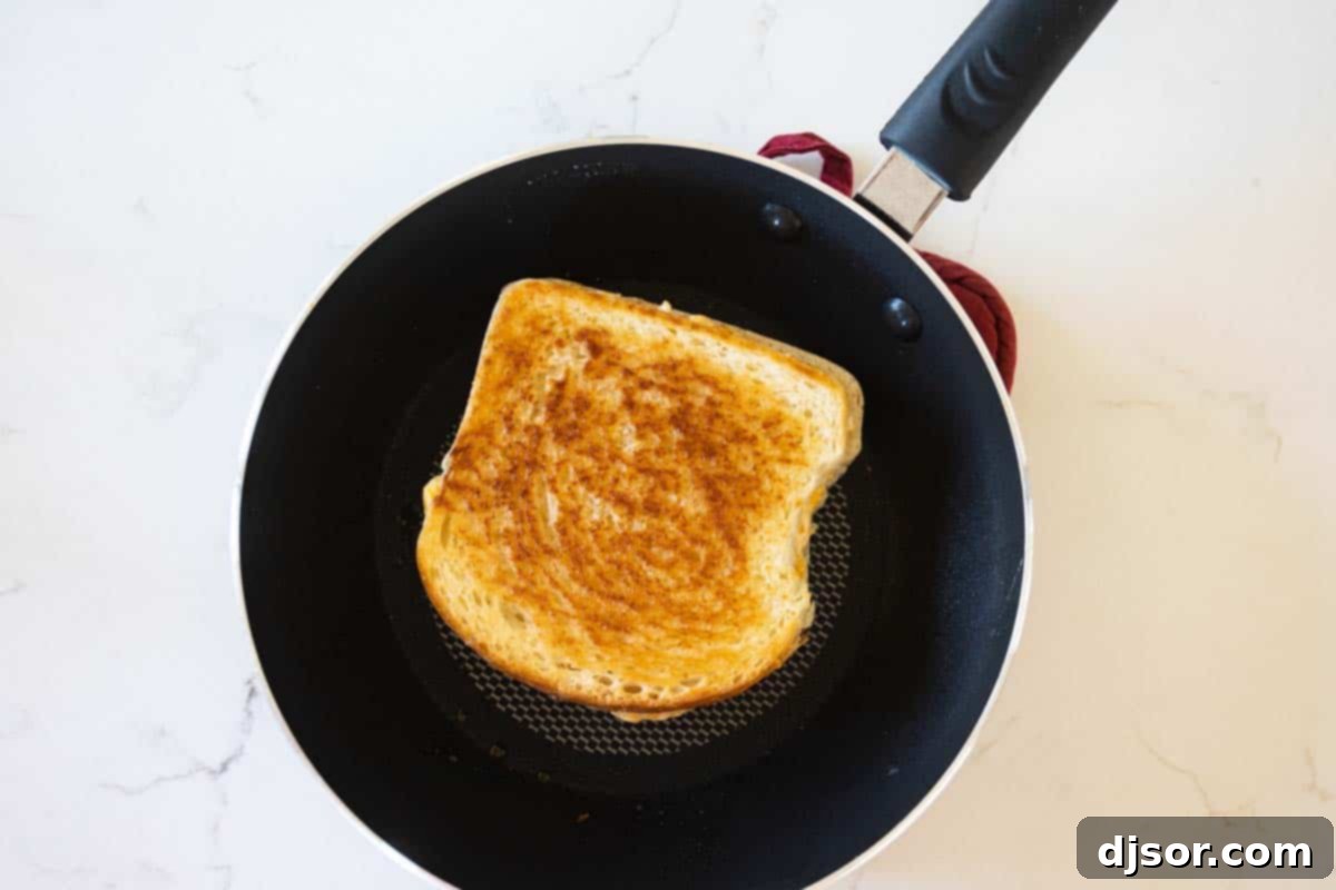 grilled cheese sandwich cooking in a skillet with a lid