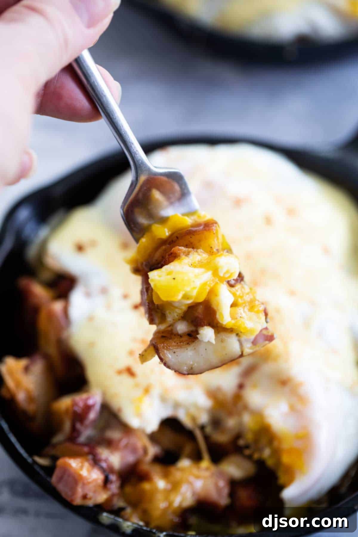 A close-up shot of someone taking a bite of the Meat and Potatoes Breakfast Skillet, showcasing the delicious layers.