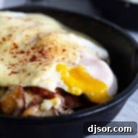 A perfectly cooked sunny-side up egg on top of a generous serving of Meat and Potatoes Breakfast Skillet, garnished with paprika.