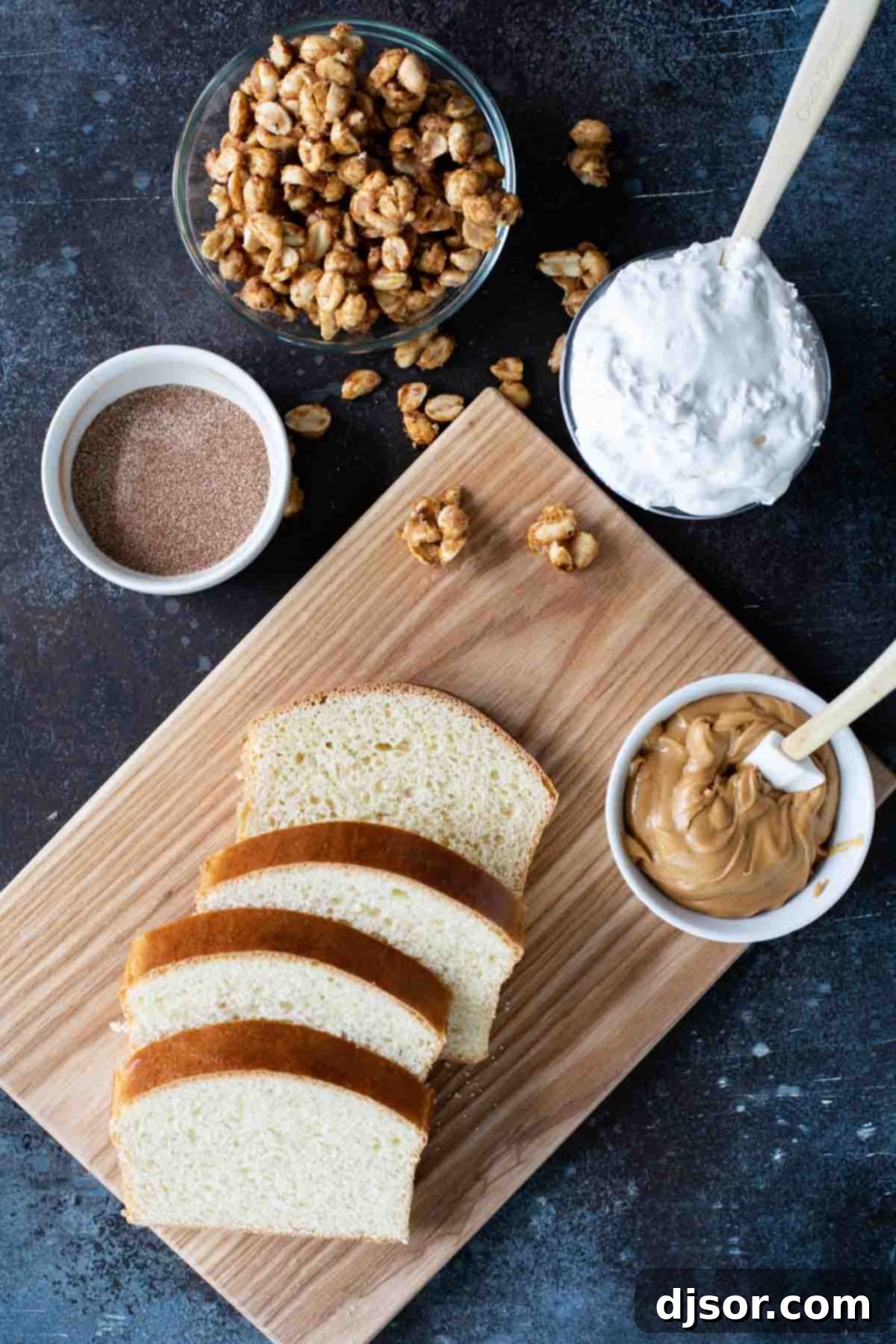 Essential ingredients for a Fluffernutter Panini: marshmallow creme, peanut butter, candied peanuts, and cinnamon sugar crusted bread, ready for assembly and grilling. A collection of ingredients laid out, ready to be transformed into a delectable Fluffernutter Panini, including peanuts, sugar, butter, bread, peanut butter, and marshmallow creme.