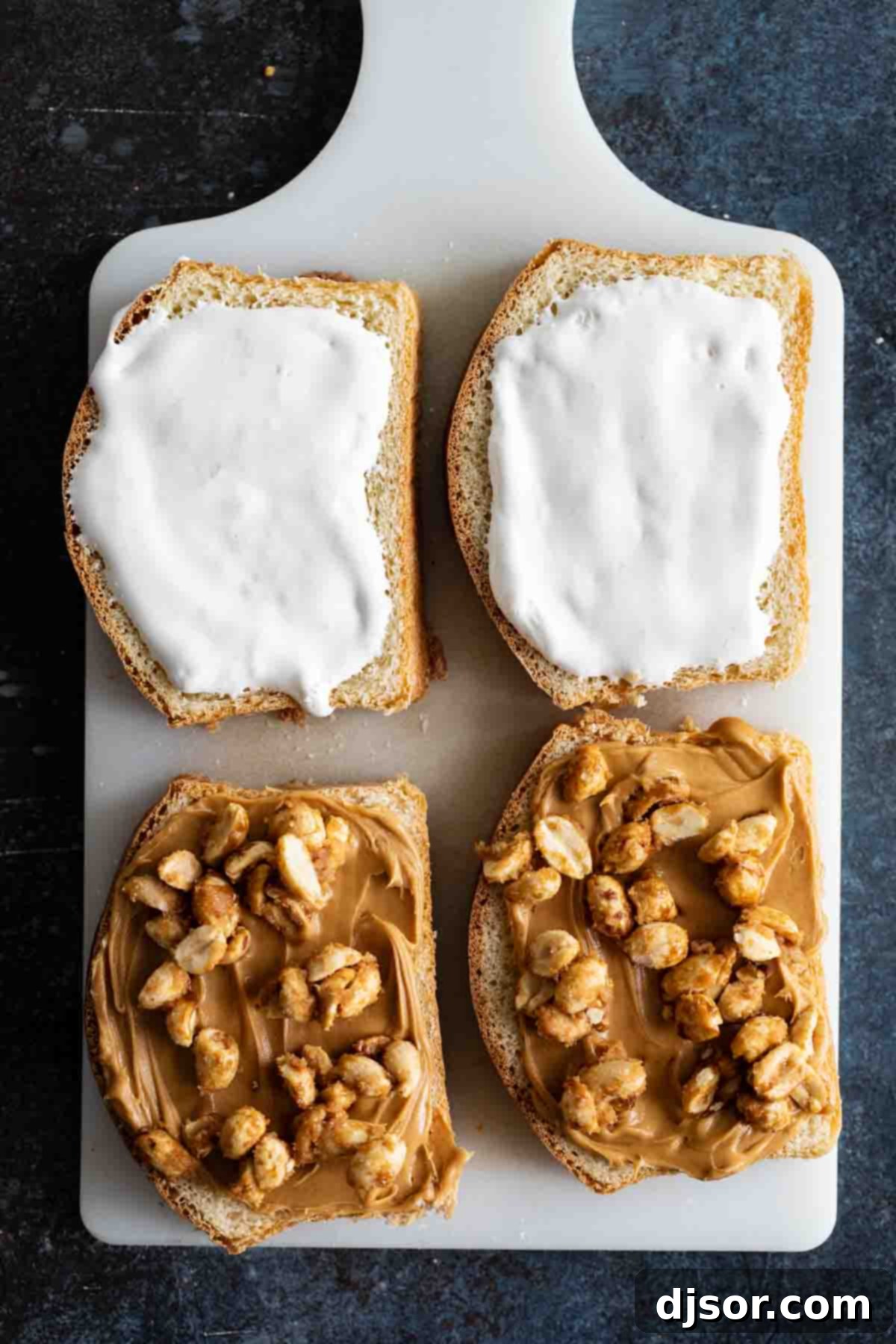The process of assembling a Fluffernutter Panini, showing the careful layering of ingredients before the sandwich is grilled to gooey perfection. Hands carefully assembling a fluffernutter sandwich, spreading peanut butter on one slice of bread and marshmallow creme on another, with candied peanuts ready to be added.
