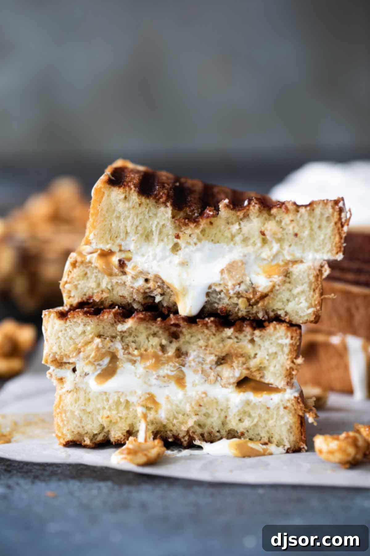 A cross-section view of a toasted Fluffernutter Panini, showcasing its delicious, melted interior with peanut butter, marshmallow, and candied peanuts. A Fluffernutter sandwich, cut in half and stacked, revealing the gooey marshmallow creme, smooth peanut butter, and crunchy candied peanuts inside.