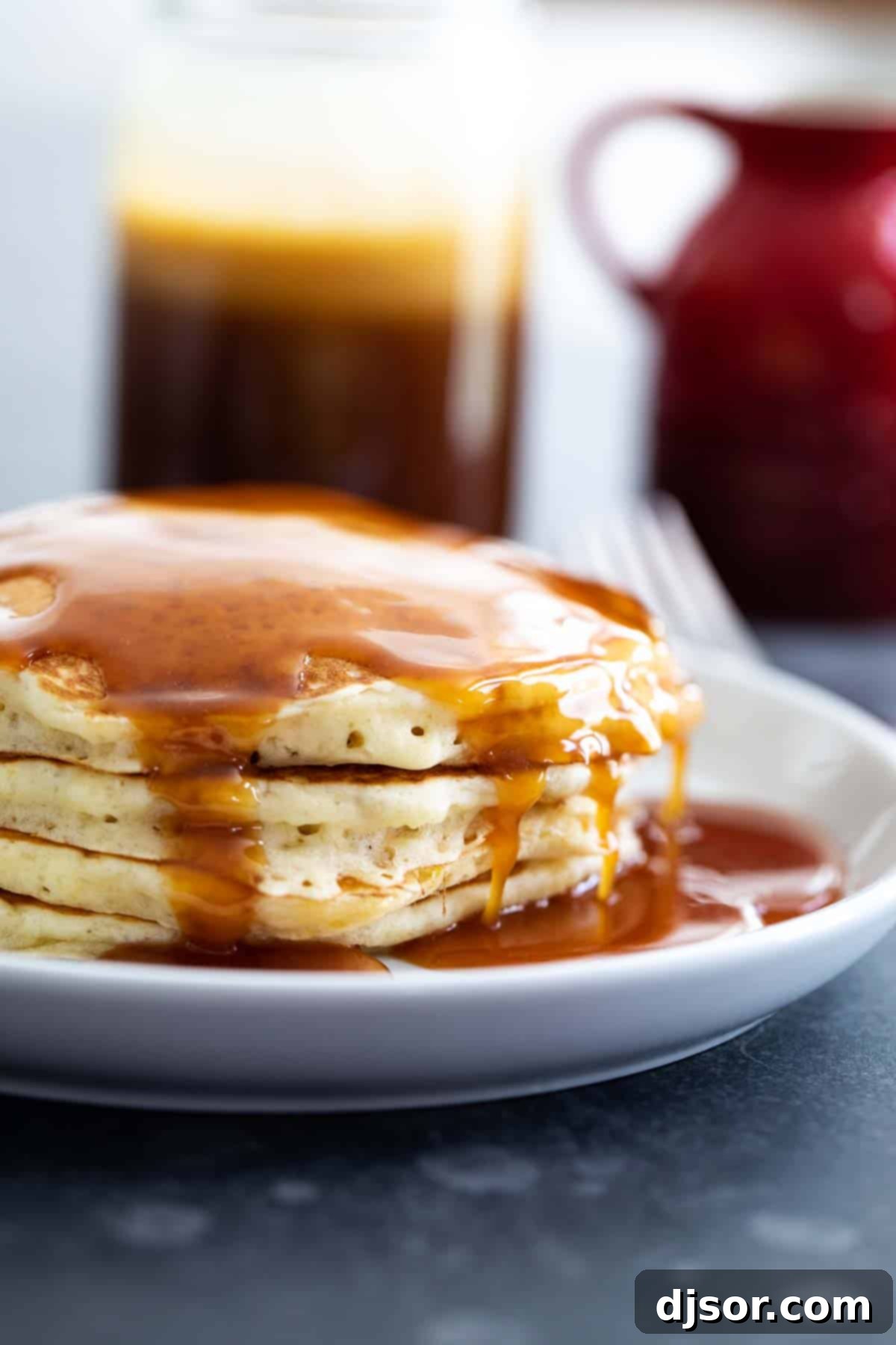 Homemade Buttermilk Syrup for Pancakes being poured onto a stack, showcasing its smooth texture