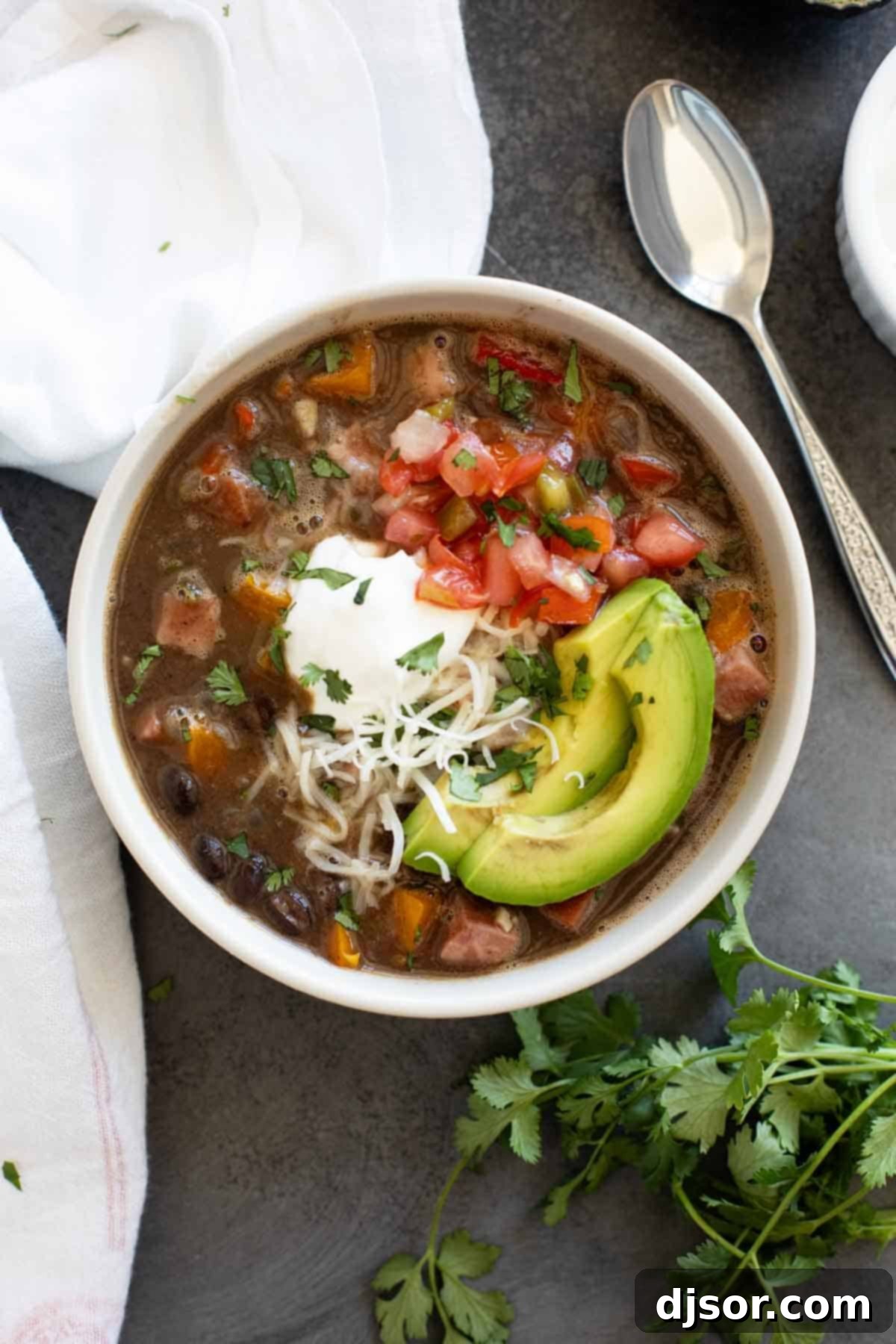 Bowl of Black Bean and Ham Soup topped with sour cream, pico de Gallo, cheese, and avocado.