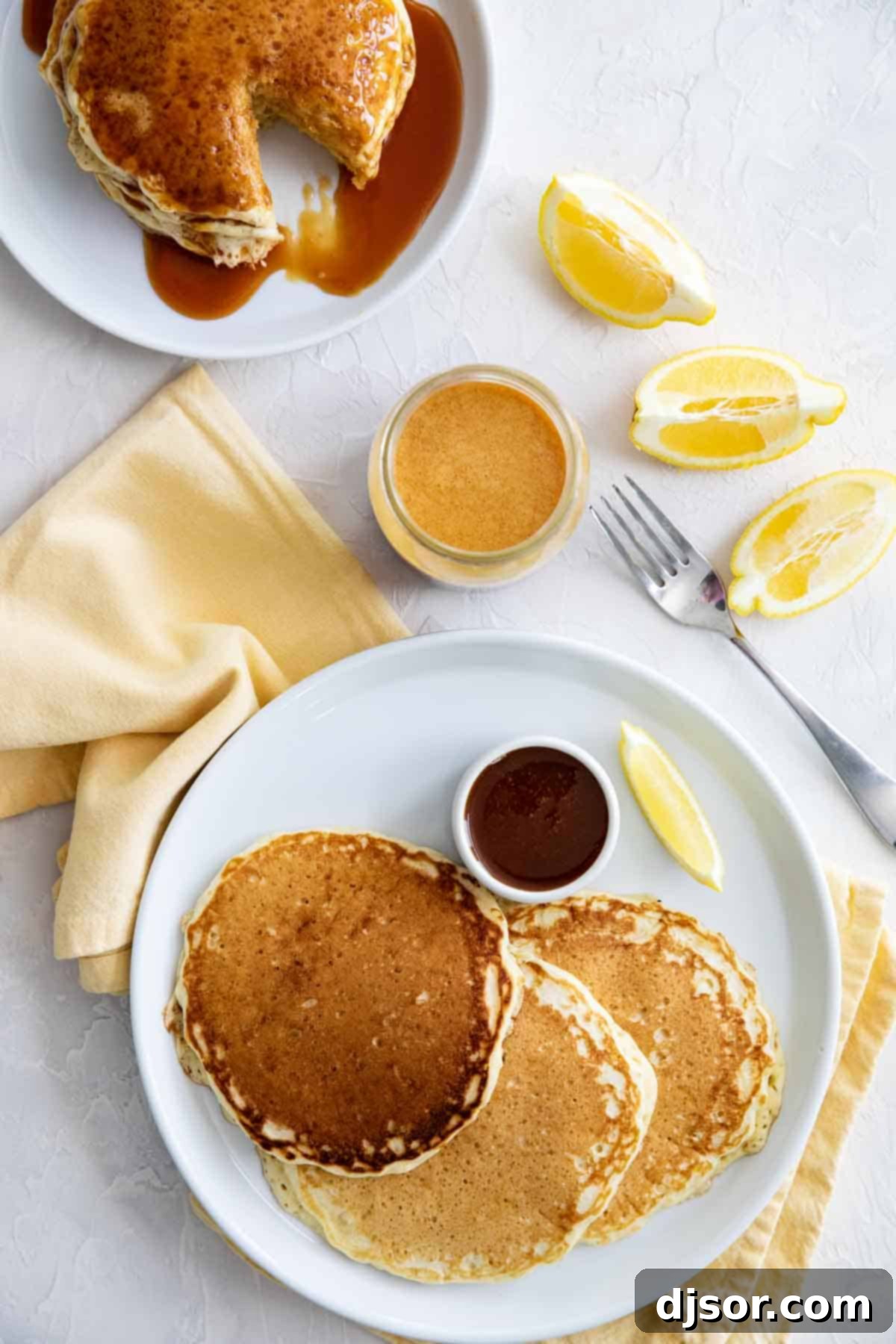 Three individual plates, each holding a perfect stack of fluffy Lemon Pancakes generously drizzled with rich homemade buttermilk syrup, ready for a family breakfast.