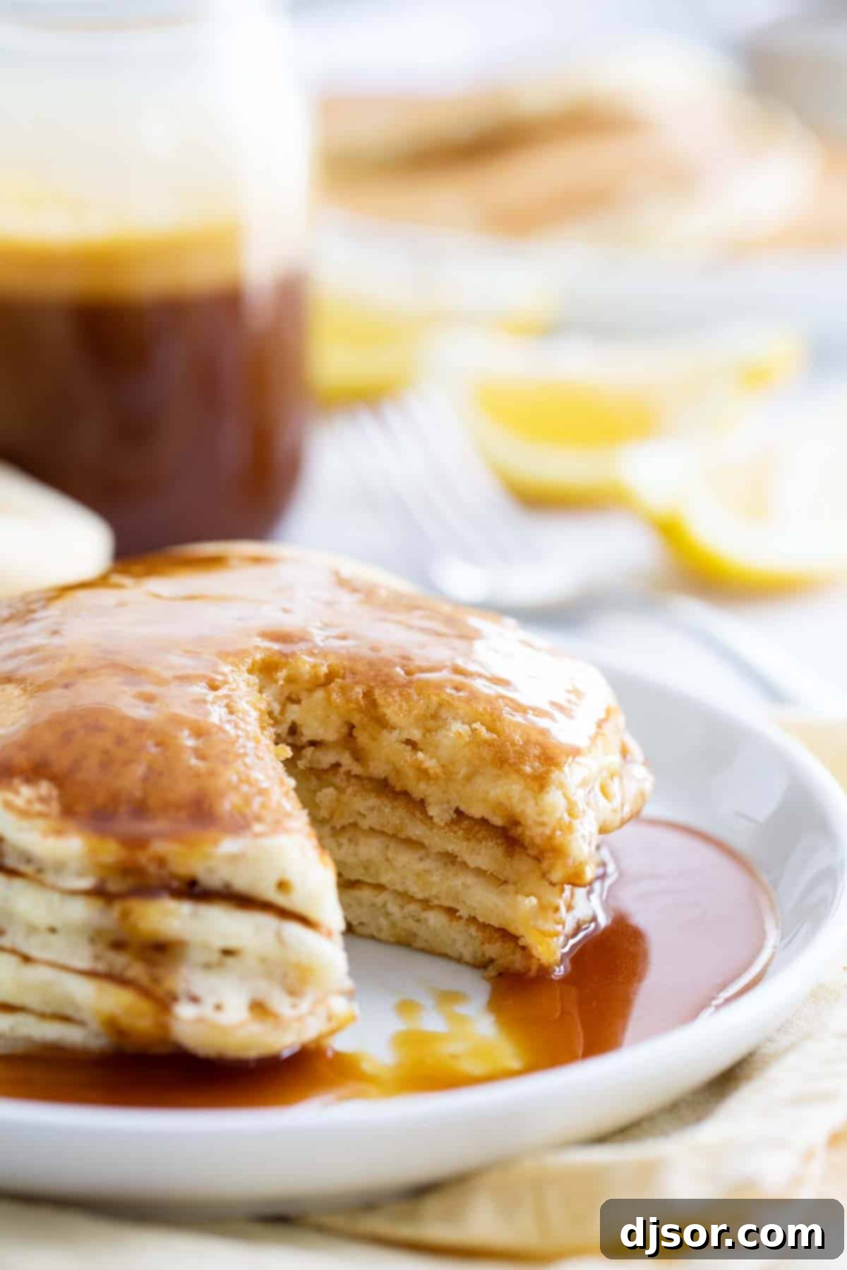 A close-up view of a stack of golden Lemon Pancakes, cut open to reveal their incredibly fluffy, airy texture and delicate crumb, highlighting their perfect lightness.
