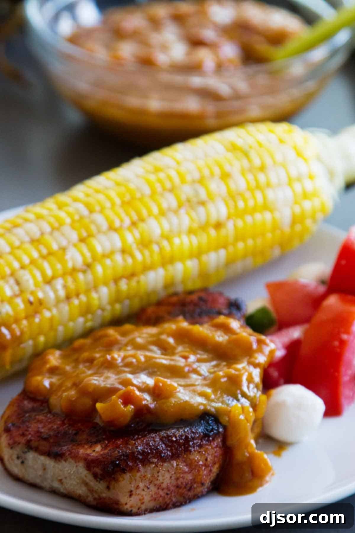 Perfectly grilled pork chops topped with a vibrant homemade mustard bacon barbecue sauce, served on a rustic plate.