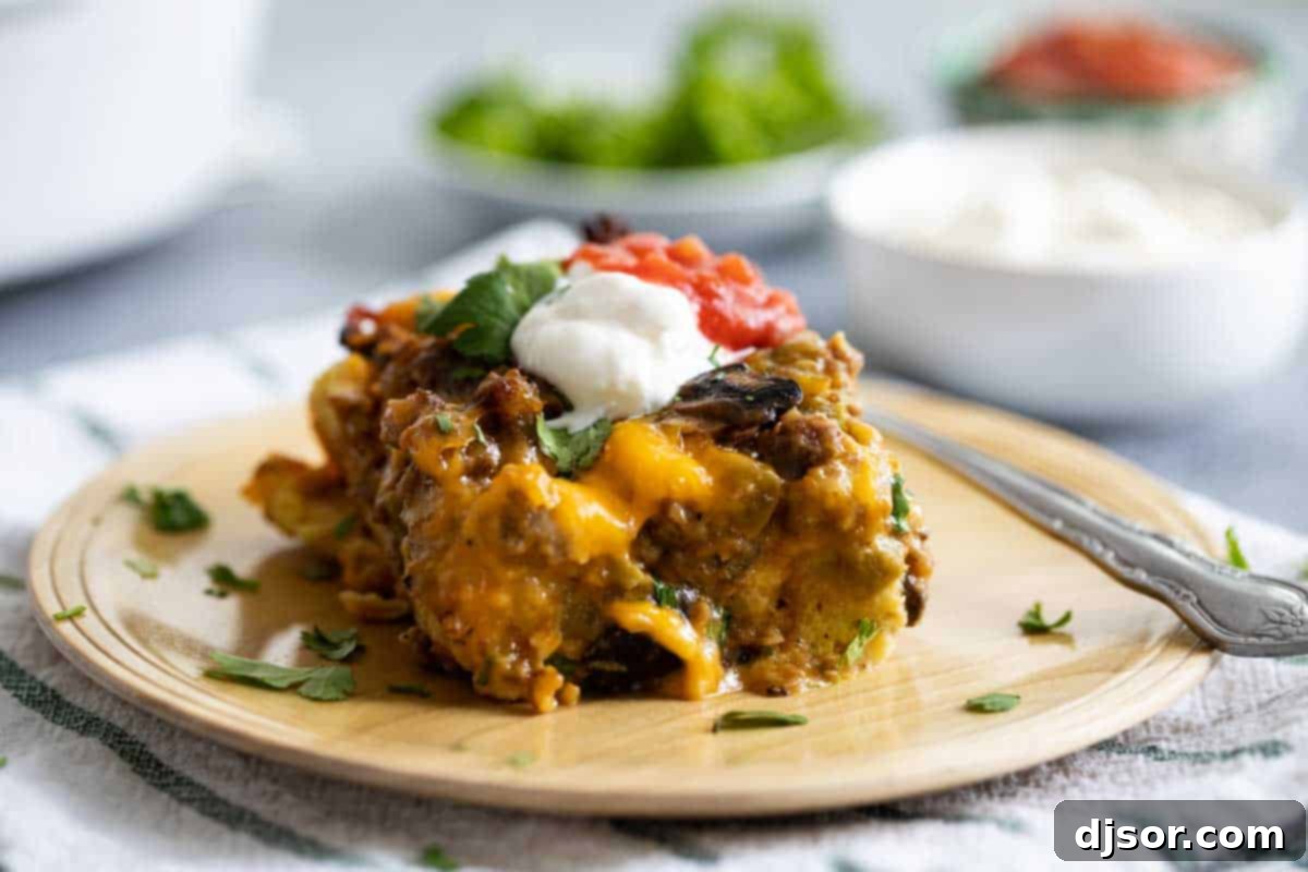 Wooden plate with a slice of Sausage Breakfast Casserole topped with sour cream and herbs.