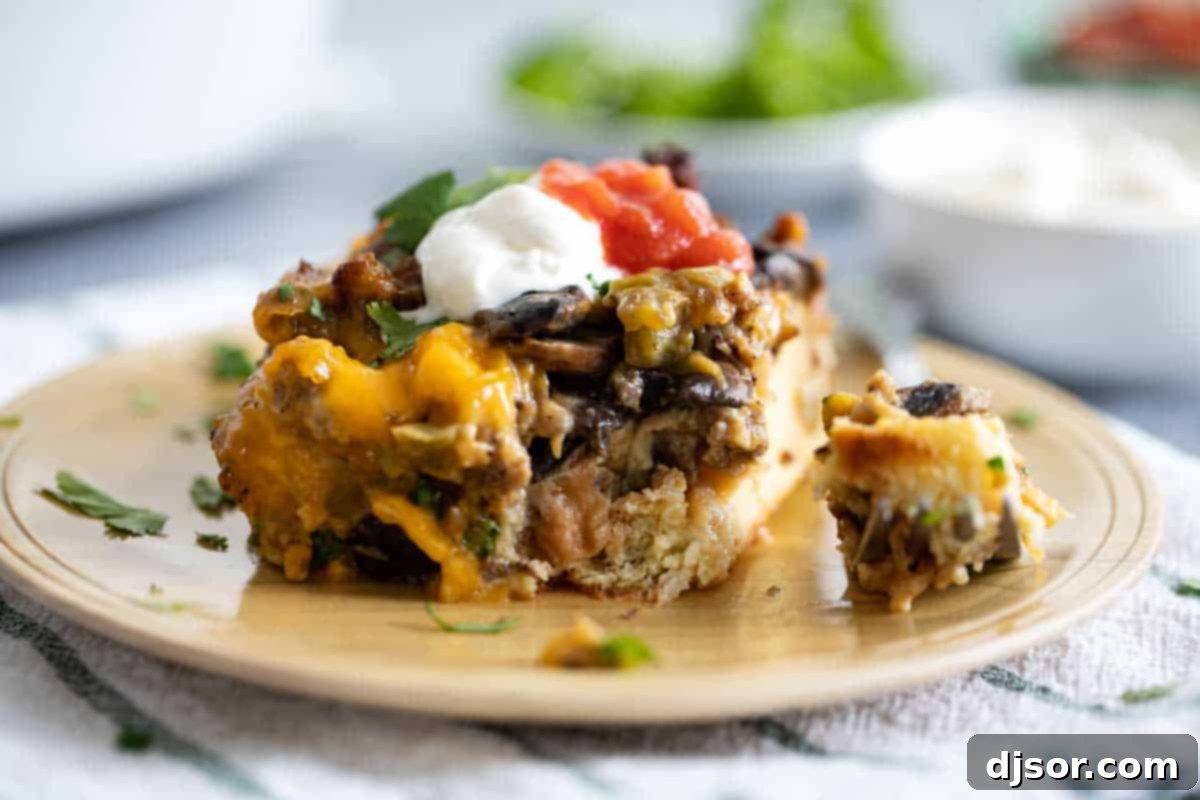 A close-up of a slice of Sausage Breakfast Casserole on a wooden plate, with a fork taking a bite.
