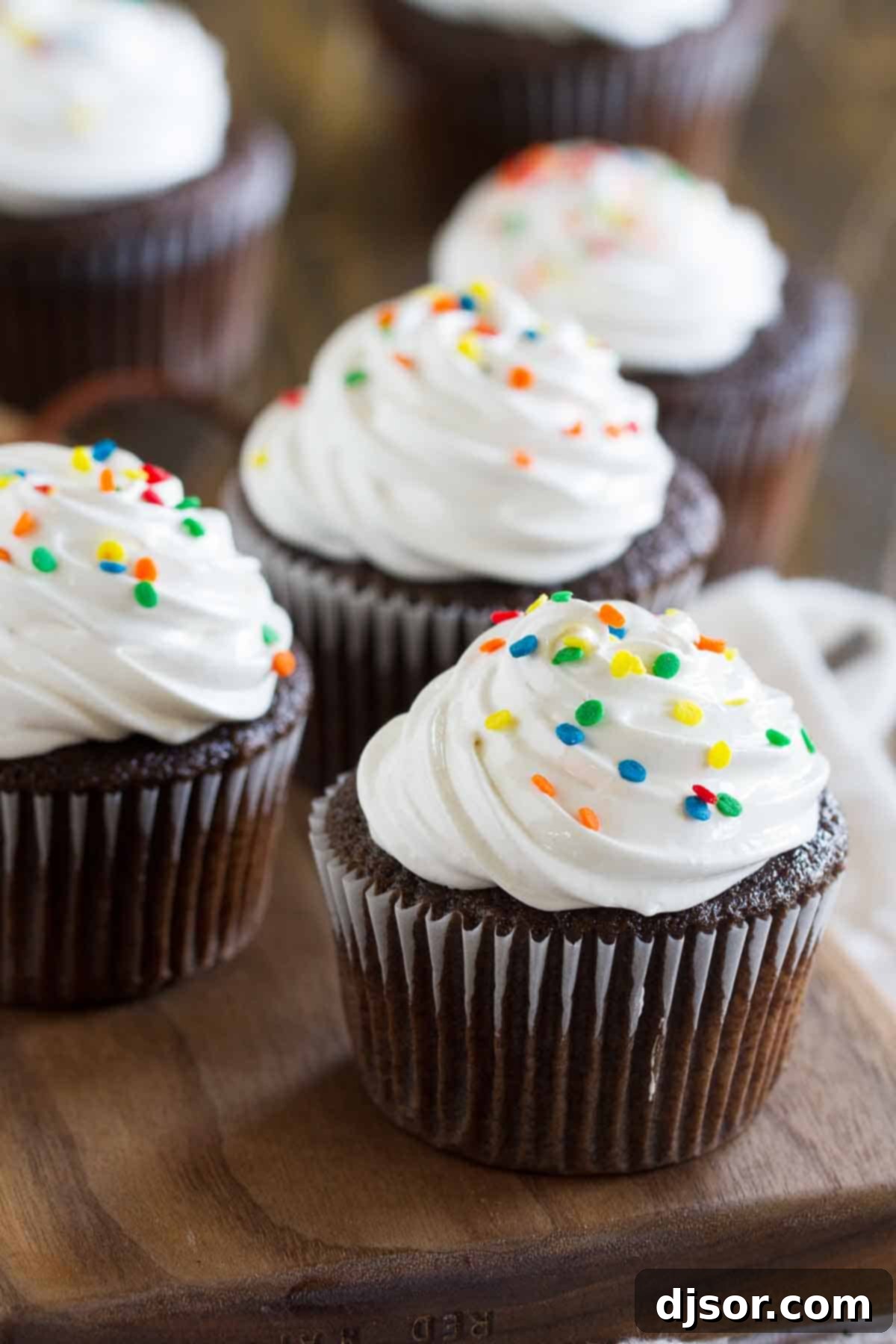 Rich Devil's Food Cupcakes generously topped with white fluffy frosting and colorful sprinkles.