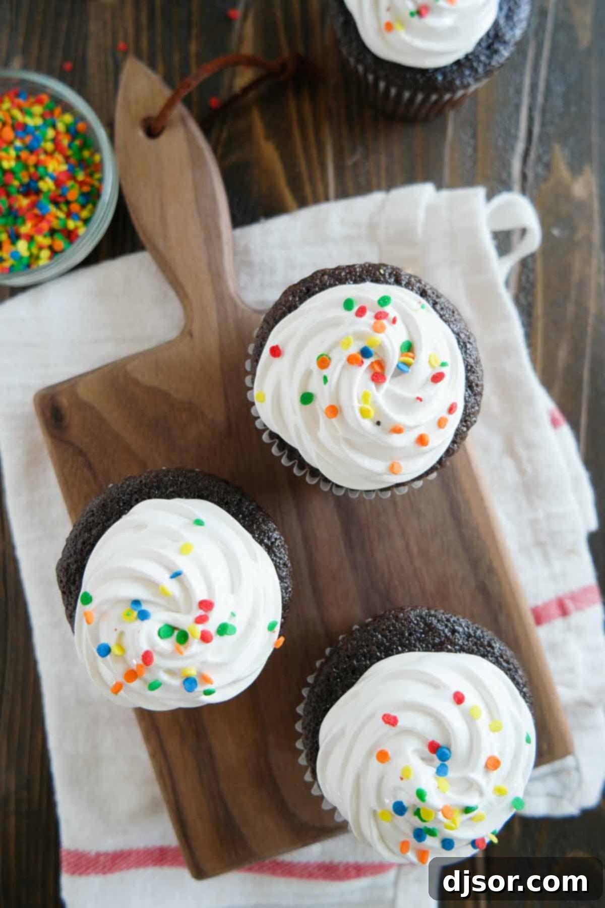 Overhead view of several Devil's Food Cupcakes, each adorned with a generous swirl of fluffy white frosting.