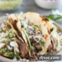 Shredded Pork Tacos topped with cabbage, onions, avocado, and more.