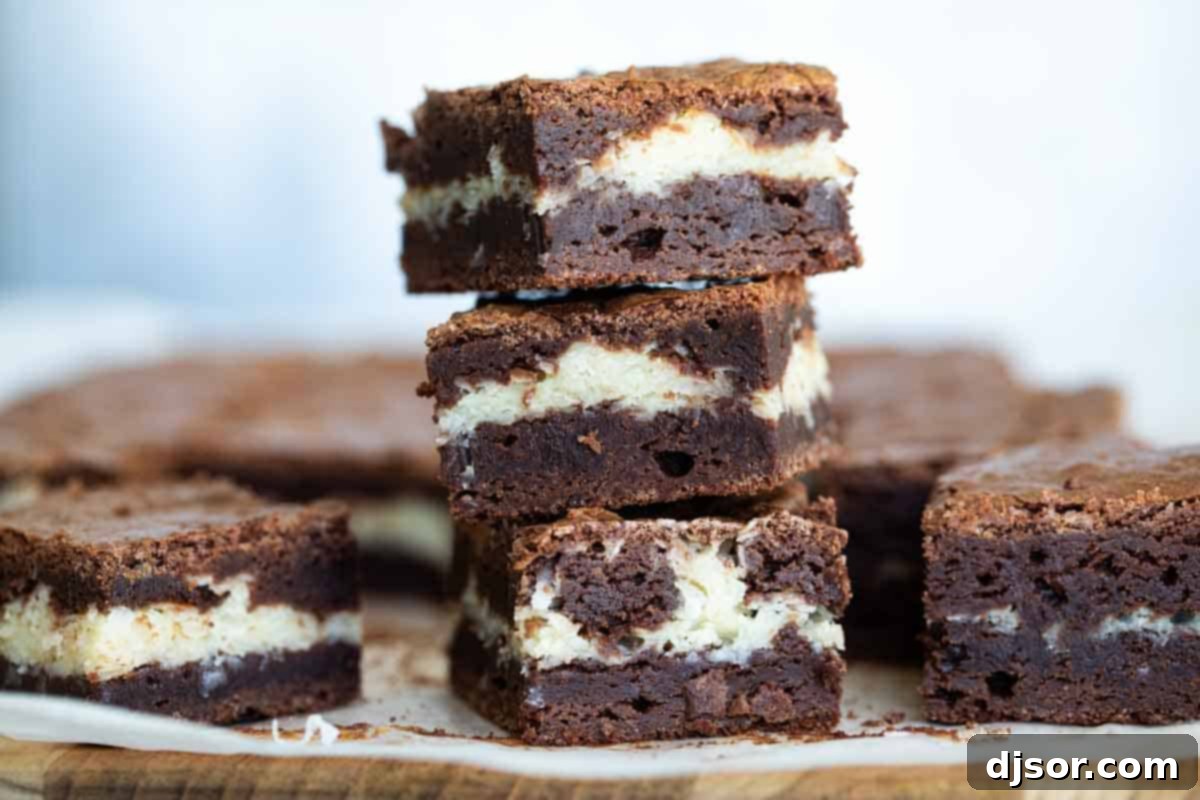 Stack of three perfectly layered coconut brownies, showcasing their rich chocolate and creamy coconut layers.