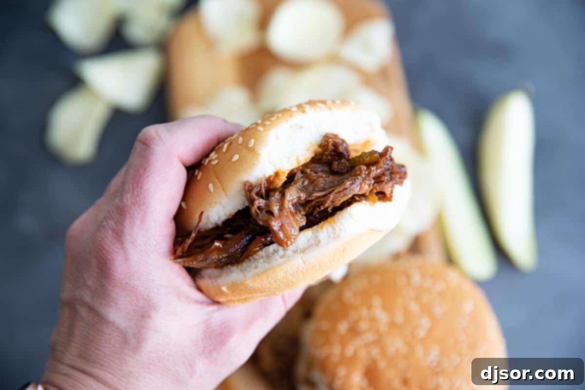 bbq beef sandwich being held with a bite taken from it