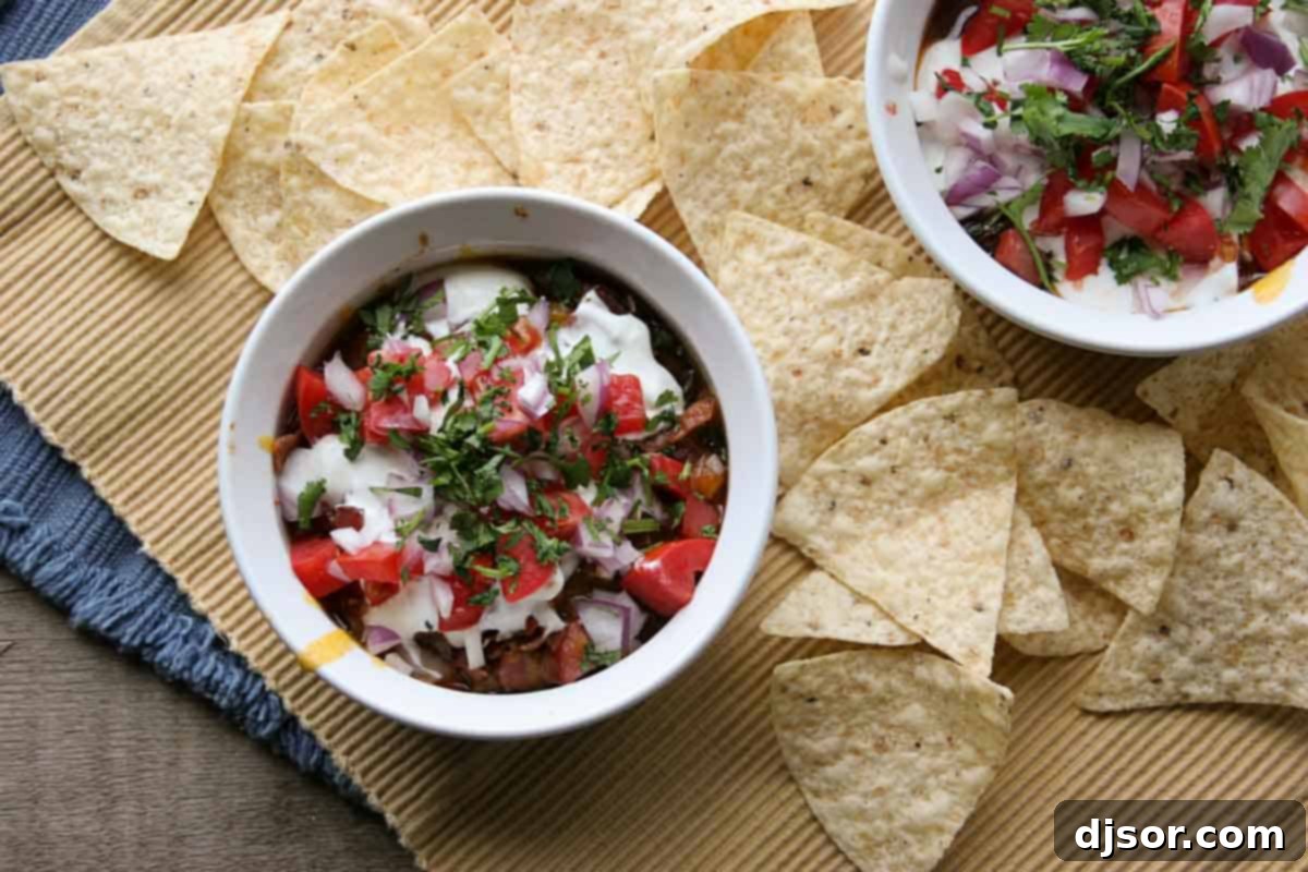 Overhead view of a vibrant 7 layer chili dog dip surrounded by tortilla chips, ready for serving