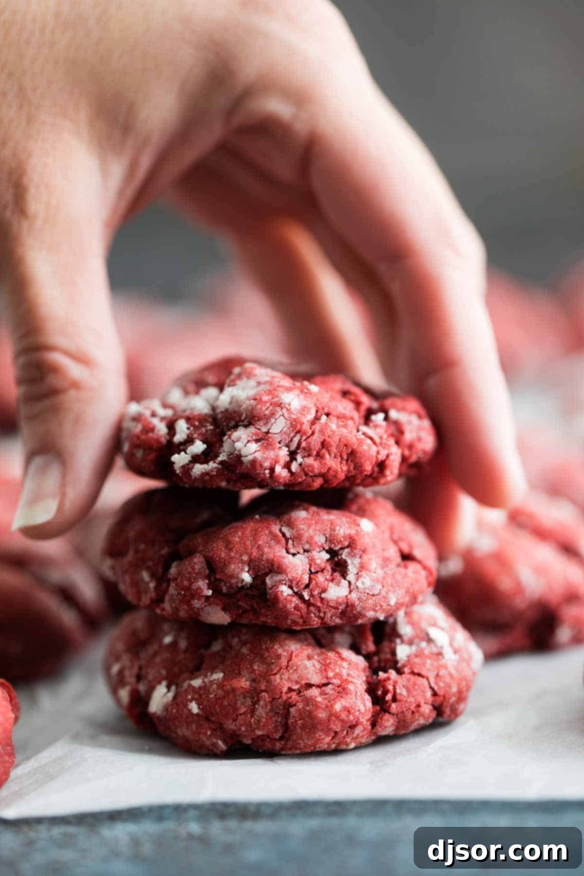 A beautiful stack of freshly baked Red Velvet Gooey Butter Cookies, generously coated in powdered sugar, ready to be enjoyed.