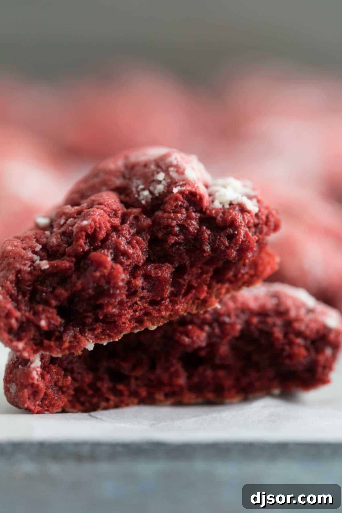 A Red Velvet Gooey Butter Cookie beautifully torn in half, revealing its incredibly soft, moist, and wonderfully gooey red interior.
