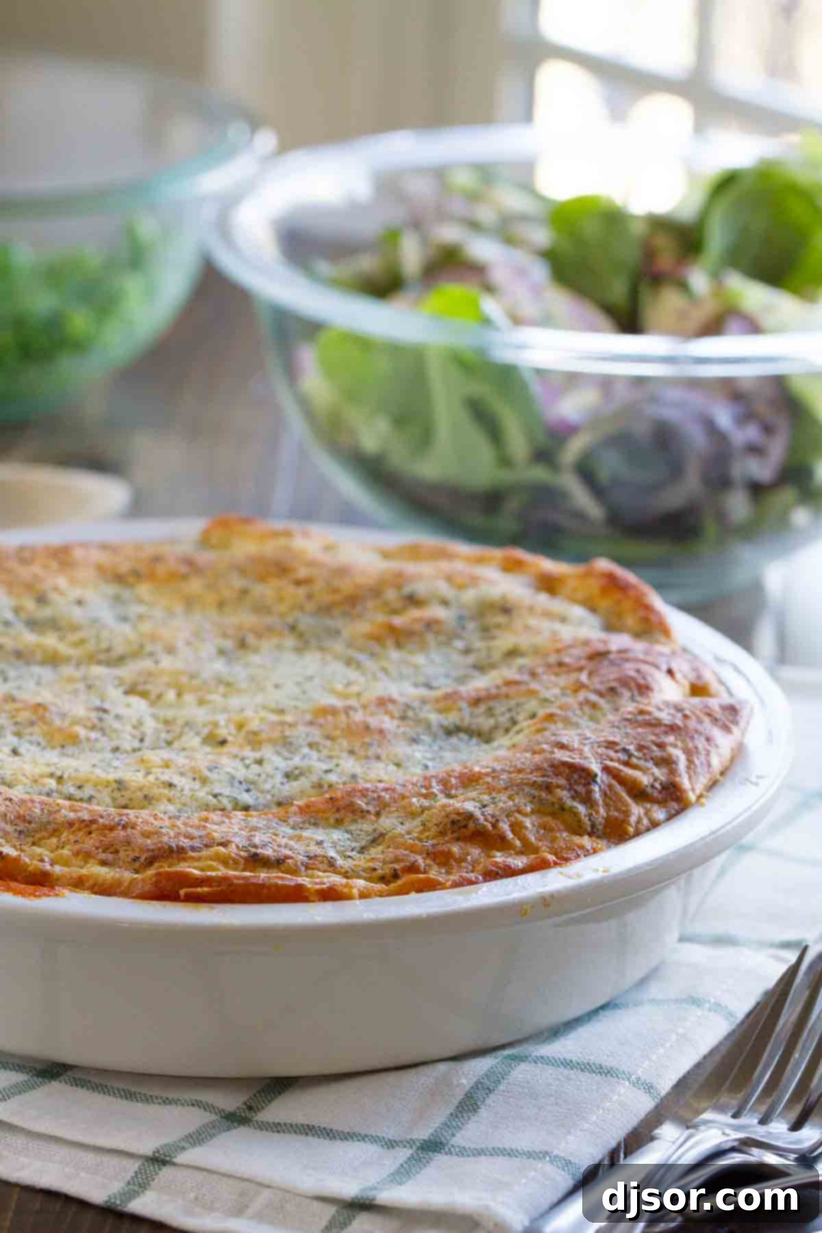 A freshly baked Zesty Italian Crescent Casserole, golden and bubbly, served with a fresh green salad. full Zesty Italian Crescent Casserole with a salad behind