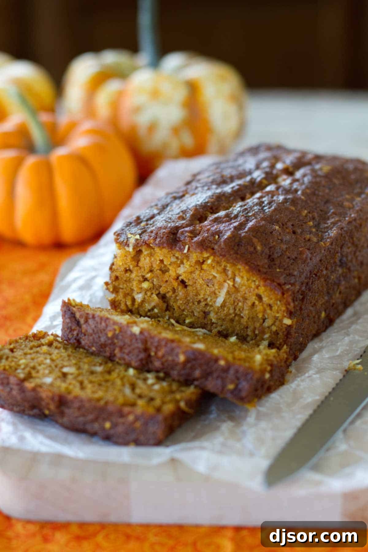 Loaf of pumpkin coconut bread with a few slices cut from it, showcasing its moist texture and golden-brown crust.