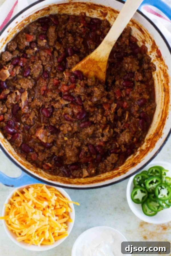 A close-up of Warm You Up Beef and Bean Chili simmering in a Dutch oven, showing the rich texture and vibrant colors of the ingredients.