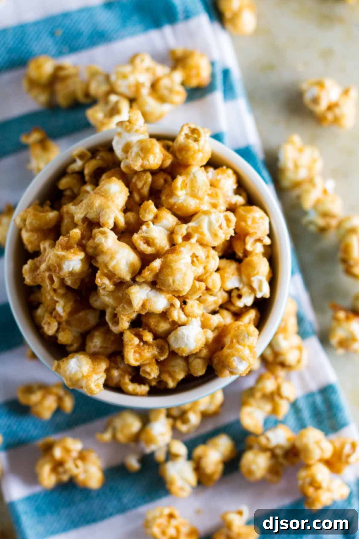 Golden Caramel Crunch Popcorn 4 Baked caramel popcorn in a bowl, spilling out to the table below, showcasing its golden crispiness