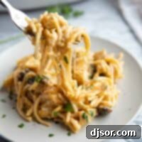 Chicken tetrazzini on a plate with a fork taking a bite, showing the creamy texture.
