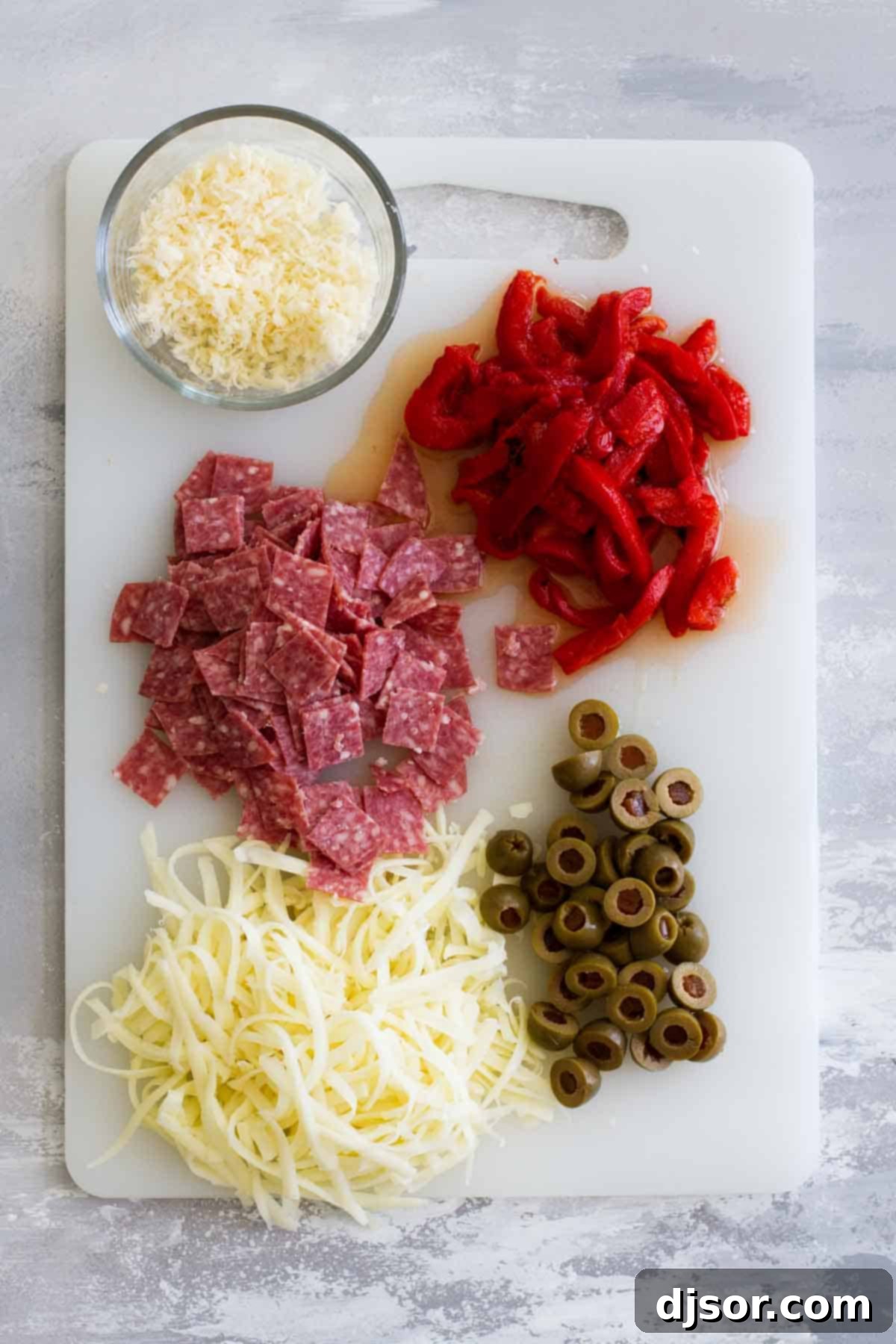Fresh Ingredients for a Gourmet Antipasto Pizza Assortment of ingredients for Antipasto Pizza including salami, olives, and roasted red peppers.