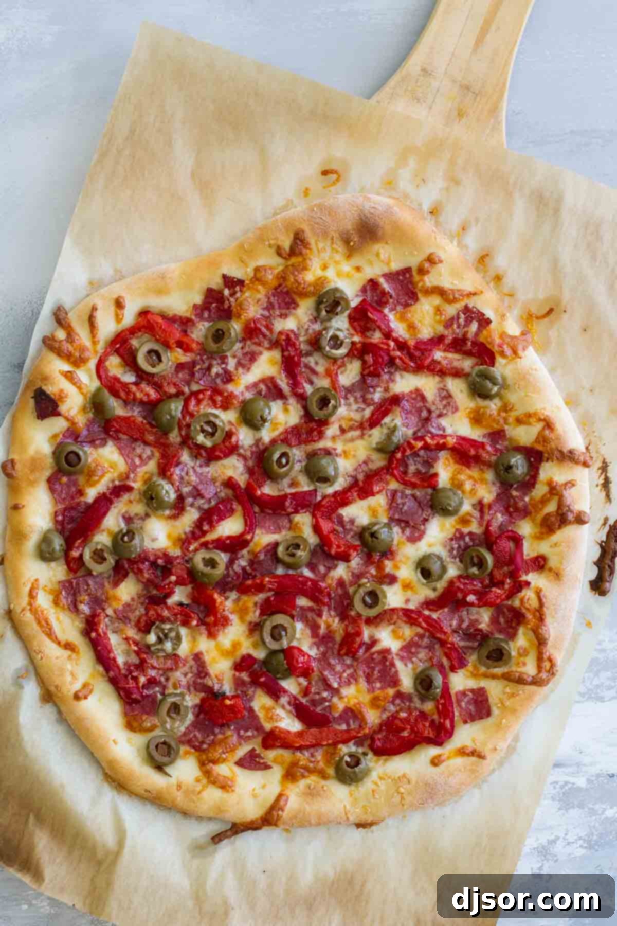 Antipasto Pizza: From Prep to Perfection Whole Antipasto Pizza with generous toppings on a pizza peel, ready for the oven.