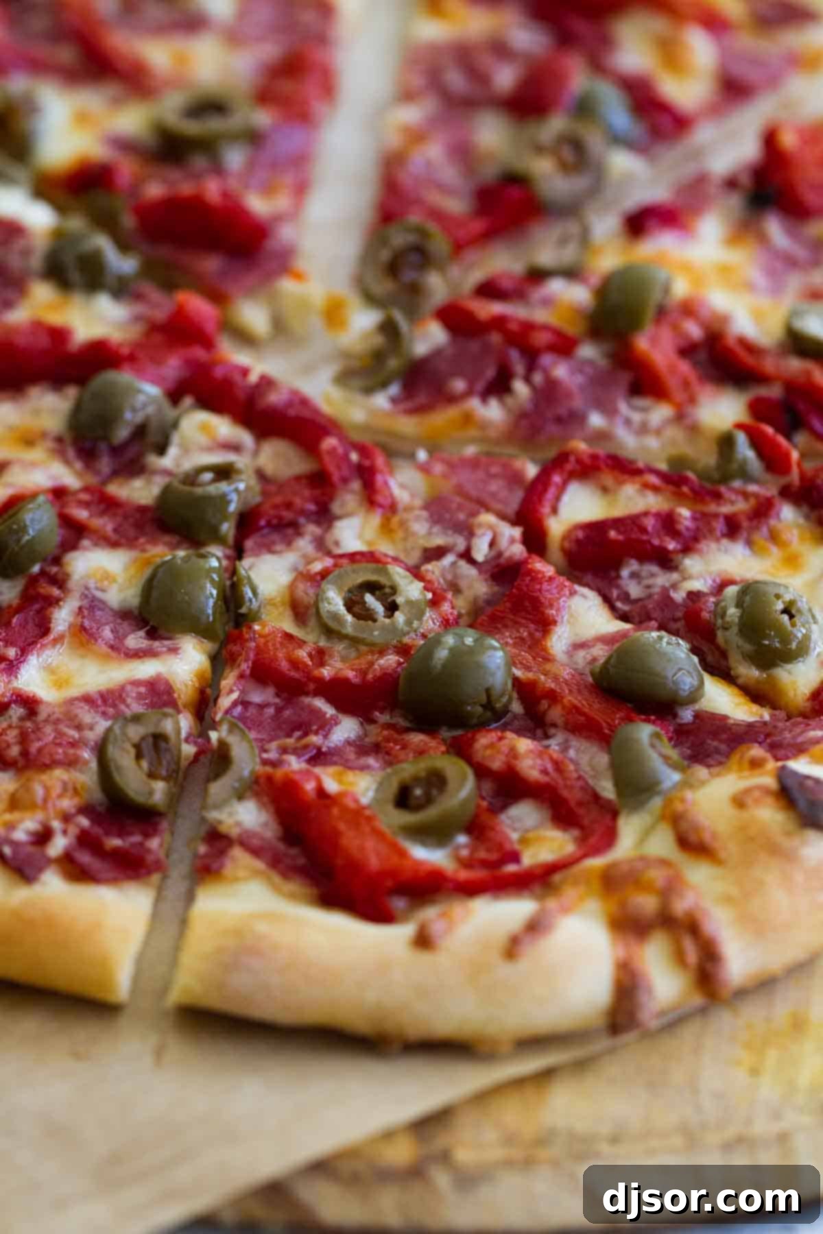 Antipasto Pizza: A Close-Up of Savory Perfection Close-up of a piece of Antipasto Pizza, highlighting the olives and cheese.