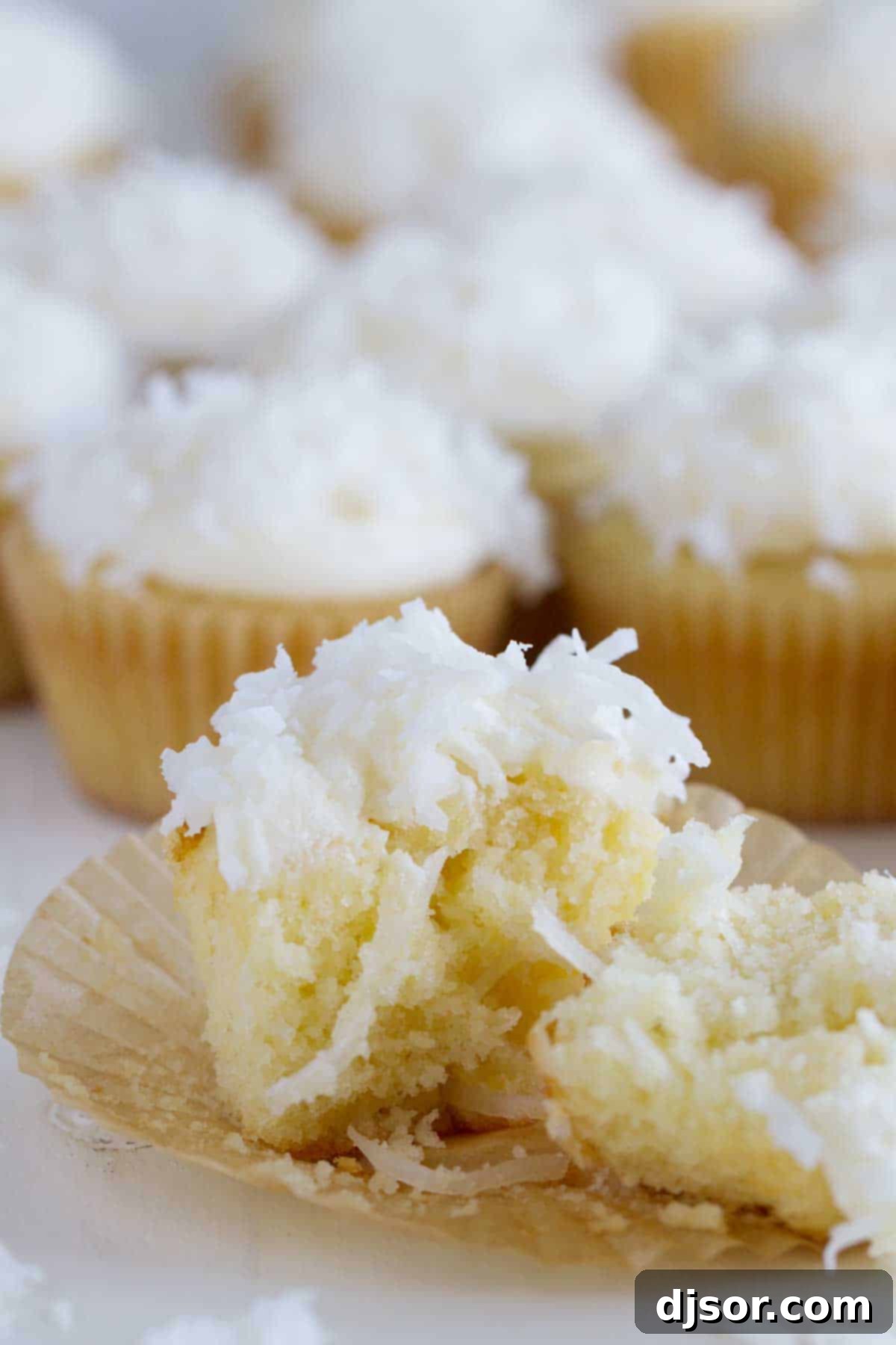 A perfectly baked coconut cupcake, sliced in half to reveal its moist interior