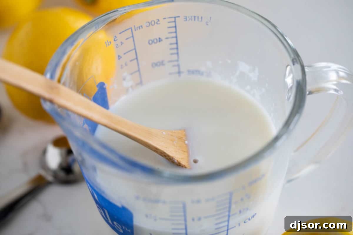 Ingredients for homemade buttermilk substitute: milk and a lemon next to a measuring cup and spoon