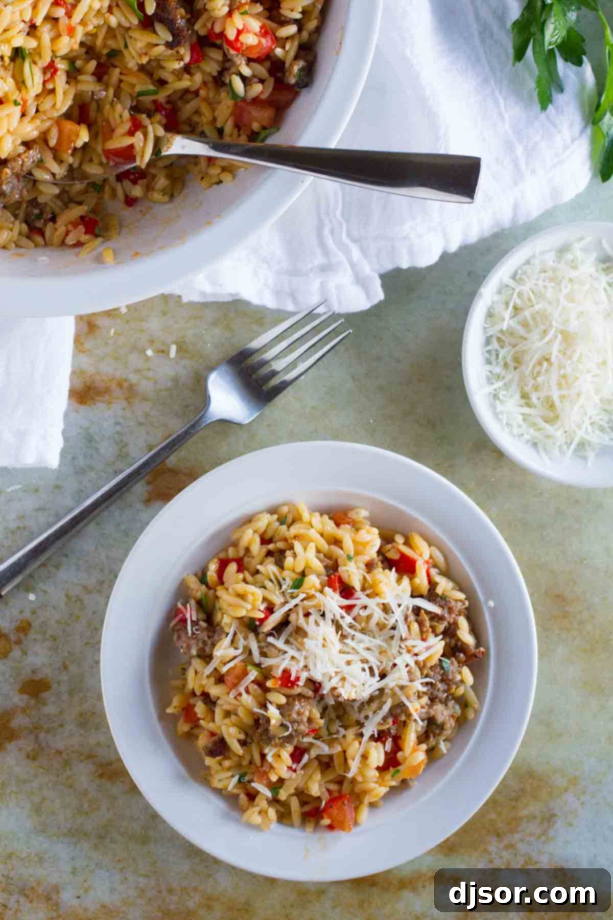 Orzo with Italian Sausage and Peppers: A Delicious, Easy Meal Enhanced with Fresh Parmesan A serving of Orzo with Italian Sausage and Peppers generously topped with grated Parmesan cheese.