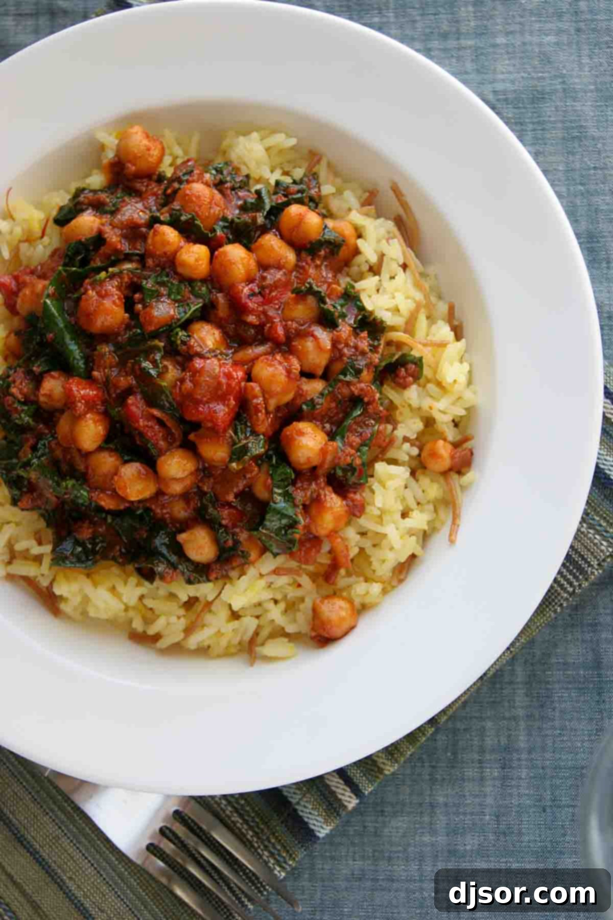 Spanish Style Rice and Beans: An Easy and Delicious Meal Idea An overhead shot of Spanish Style Rice and Beans, meticulously plated to showcase the rich colors and inviting textures of the seasoned rice, tender chickpeas, crumbled chorizo, and vibrant kale leaves.