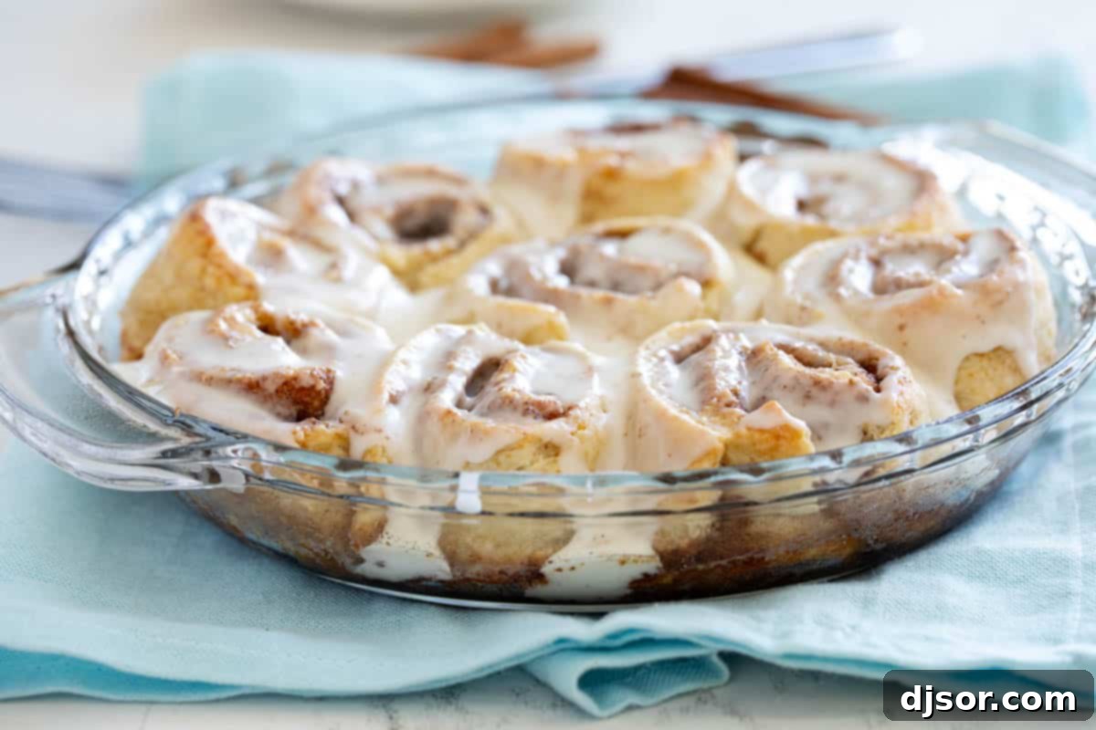Delightful homemade cinnamon biscuits generously topped with sweet icing, nestled in a rustic pie dish, ready for serving.