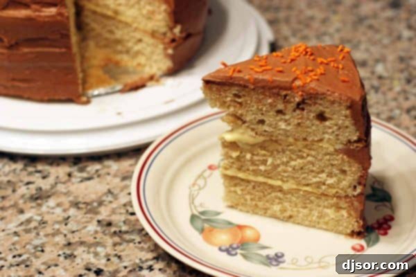 A delicious slice of Sweet Potato Cake revealing its moist layers, orange cream filling, and chocolate cream cheese frosting, ready to be enjoyed.