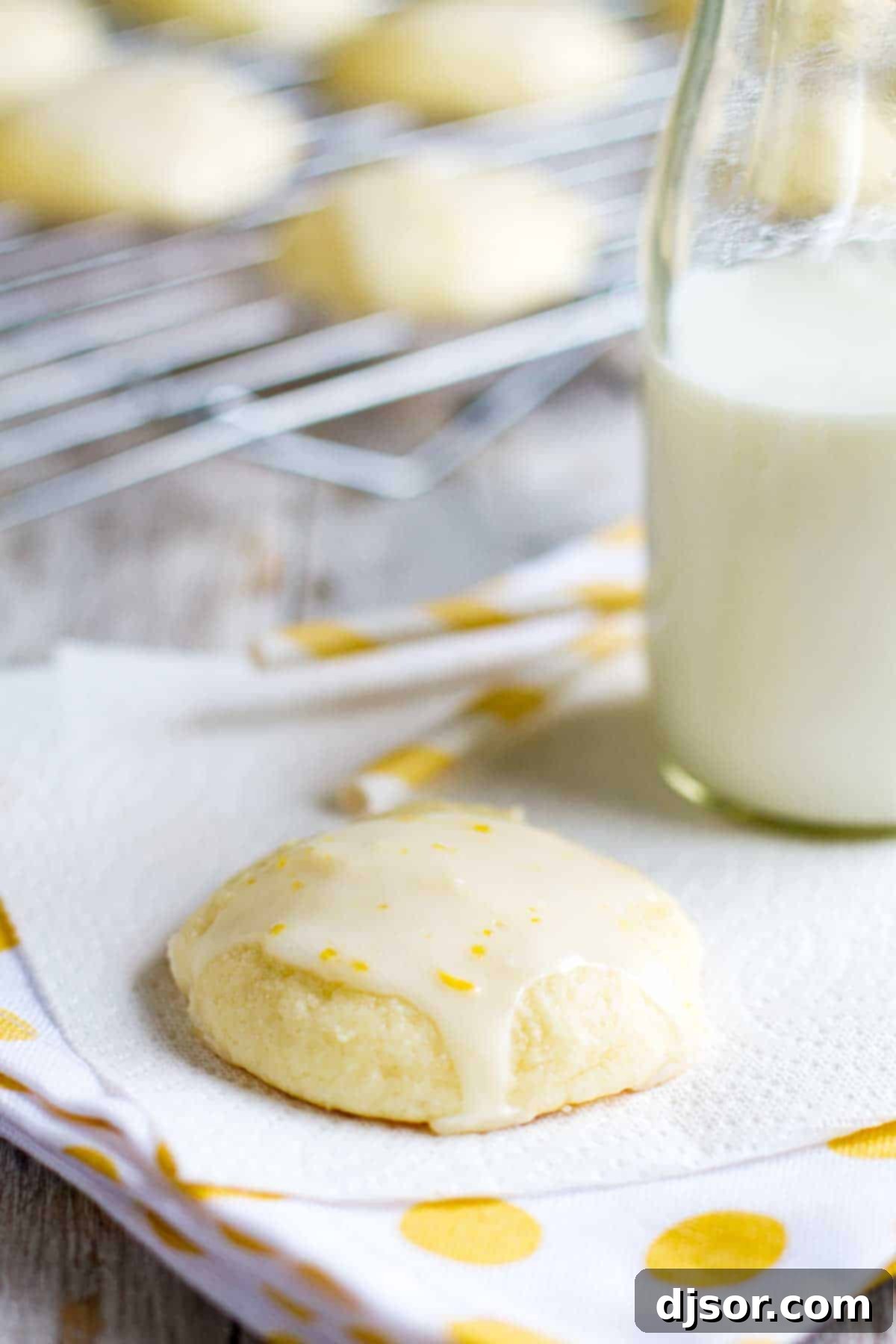 Lemon Ricotta Cookie on a napkin with milk and straws, highlighting its soft texture and lemon glaze
