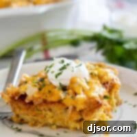 A delicious slice of Chicken Tamale Casserole, topped with sour cream, showcasing the layers of corn crust, chicken, and cheese.