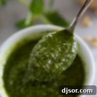 Spoonful of fresh basil pesto over a bowl.